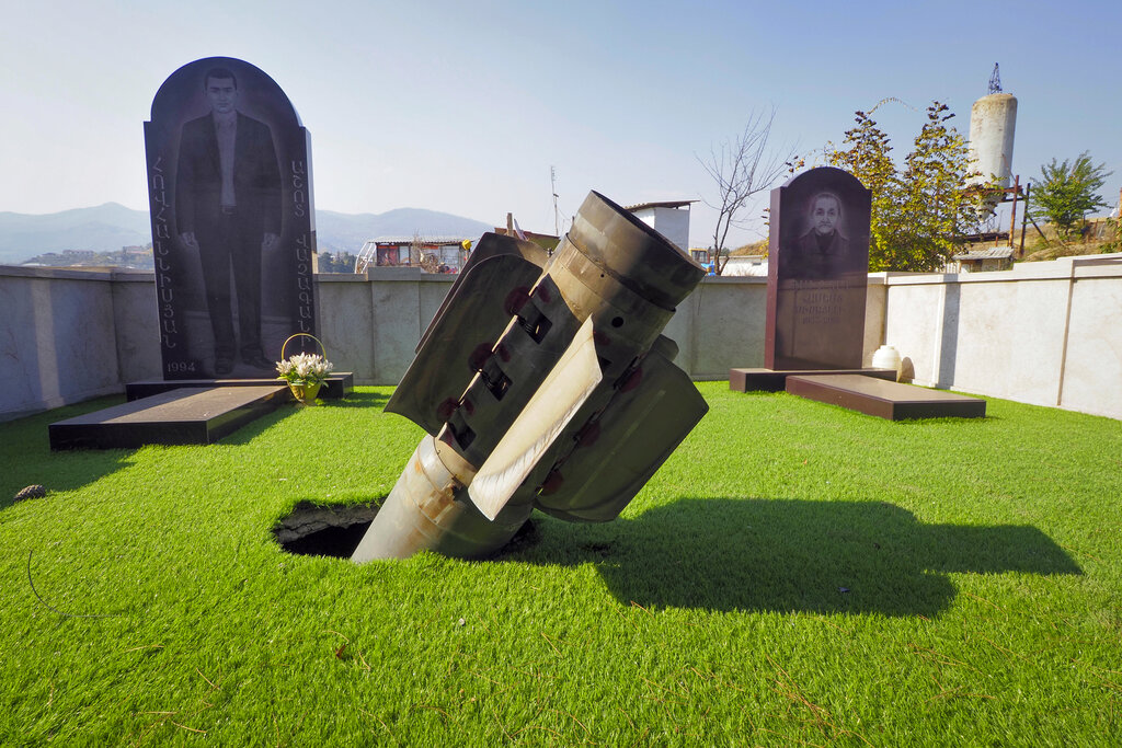 The tail of an unexploded multiple rocket 'Smerch' sticks out in a tomb at a cemetery after shelling by Azerbaijan's artillery in Stepanakert, the separatist region of Nagorno-Karabakh, Sunday, Nov. 1, 2020. Fighting over the separatist territory of Nagorno-Karabakh entered sixth week on Sunday, with Armenian and Azerbaijani forces blaming each other for new attacks. (AP Photo)