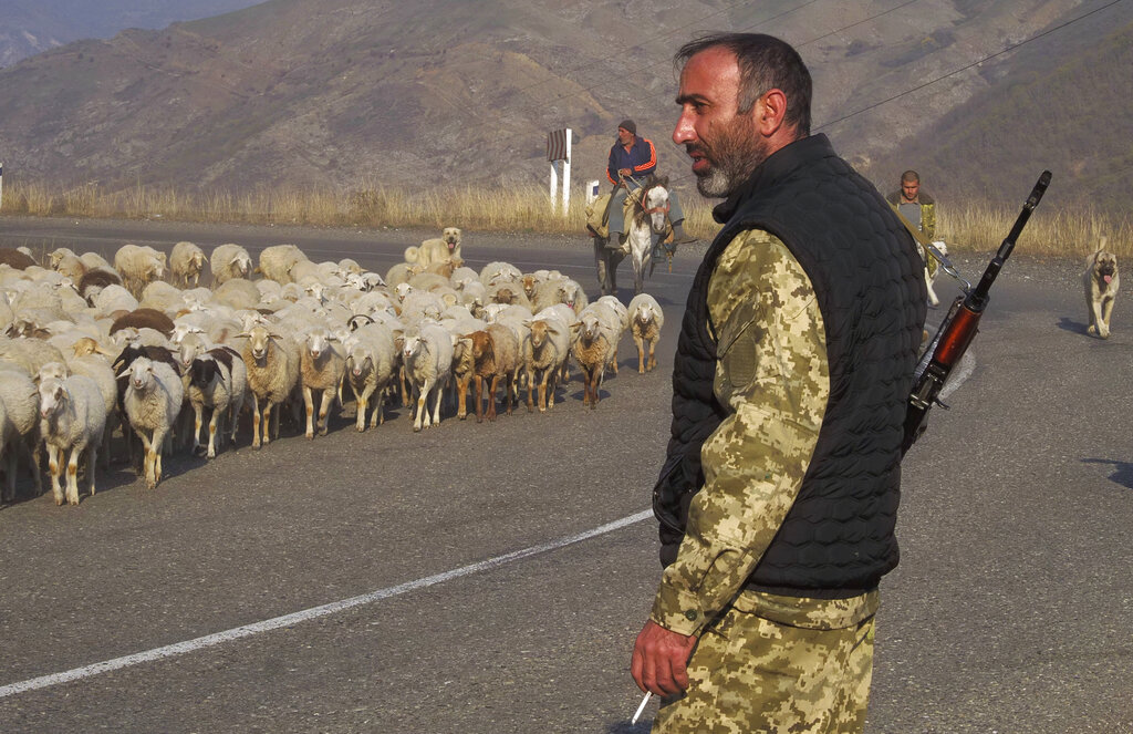 An ethnic Armenian soldier looks at flock of sheep driven away from the front line outside Berdzor, the separatist region of Nagorno-Karabakh, Sunday, Nov. 1, 2020.  Fighting over the separatist territory of Nagorno-Karabakh entered sixth week on Sunday, with Armenian and Azerbaijani forces blaming each other for new attacks. (AP Photo)