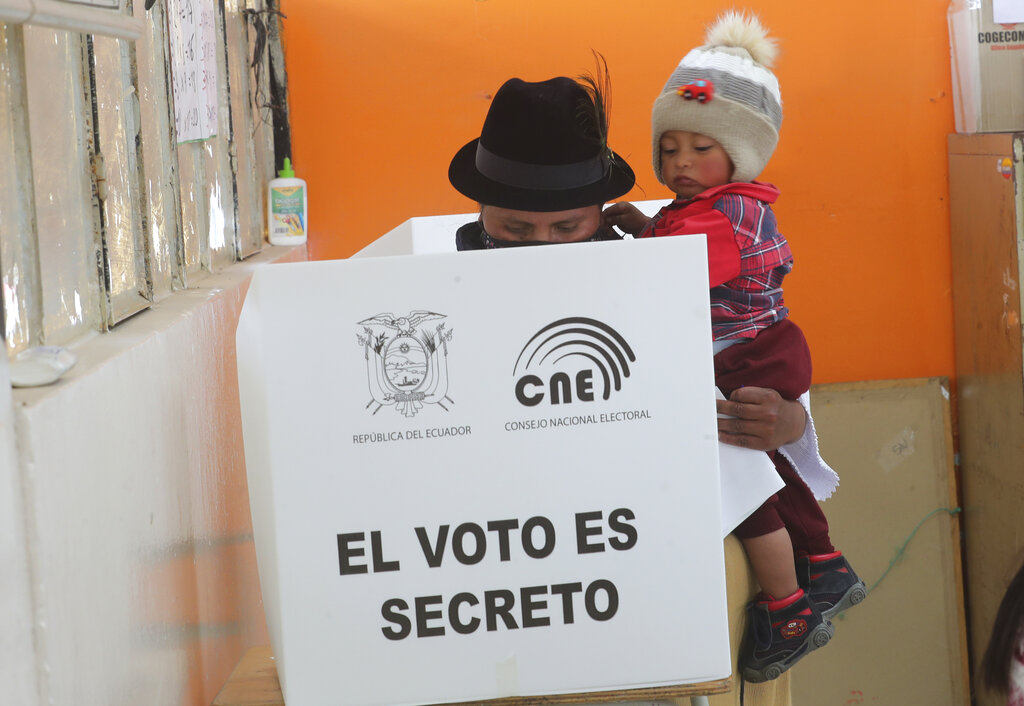 A woman carries her son as she casts her ballot in a general election, in Cangahua, Ecuador, Sunday, Feb. 7, 2021. Amidst the new coronavirus pandemic, Ecuadoreans went to the polls in a first-round presidential and legislative election.  (AP Photo/Dolores Ochoa)