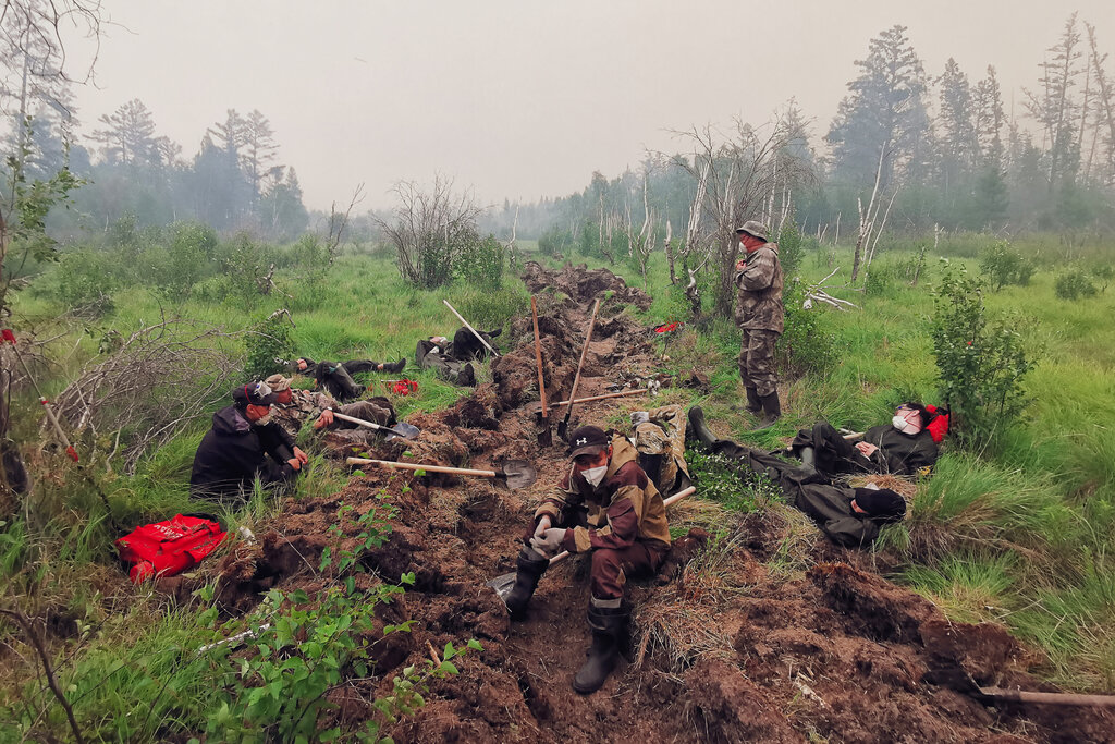 Volunteers rest as they dig a moat to stop a forest fire in the republic of Sakha also known as Yakutia, Russia Far East, Saturday, July 17, 2021. Russia has been plagued by widespread forest fires, blamed on unusually high temperatures and the neglect of fire safety rules, with the Sakha-Yakutia region in northeastern Siberia being the worst affected. (AP Photo/Ivan Nikiforov)