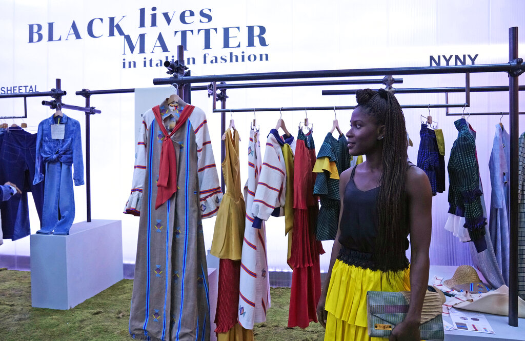 Fashion designer Fallylah Nyny Ryke Goungou, from Togo, poses in front her creations, part of the Black Lives Matter Spring Summer 2022 collective fashion event, unveiled during the Milan Fashion Week, in Milan, Italy, Tuesday, Sept. 21, 2021. (AP Photo/Antonio Calanni)