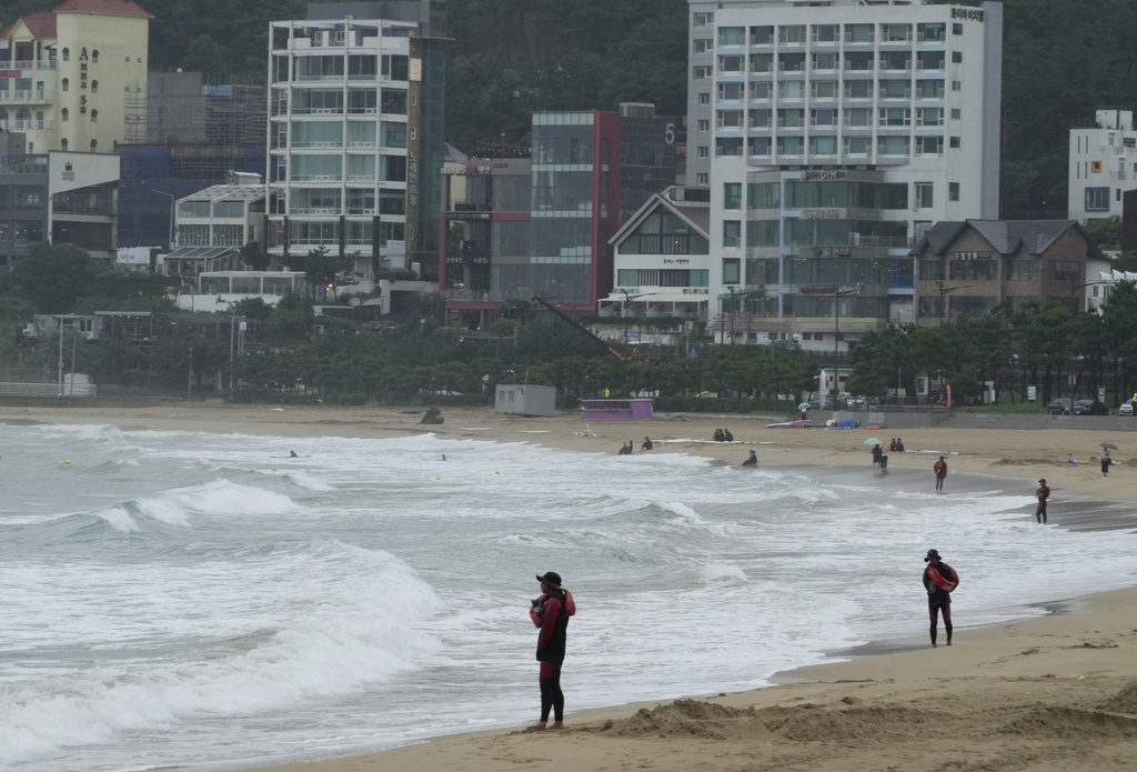 Water lifeguards stand on a beach as the tropical storm named Khanun approaches to the Korean Peninsular, in Busan, South Korea, Wednesday, Aug. 9, 2023. Dozens of flights and ferry services were grounded in South Korea on Wednesday ahead of the tropical storm that has dumped heavy rain on Japan's southwestern islands for more than a week. (AP Photo/Ahn Young-joon)