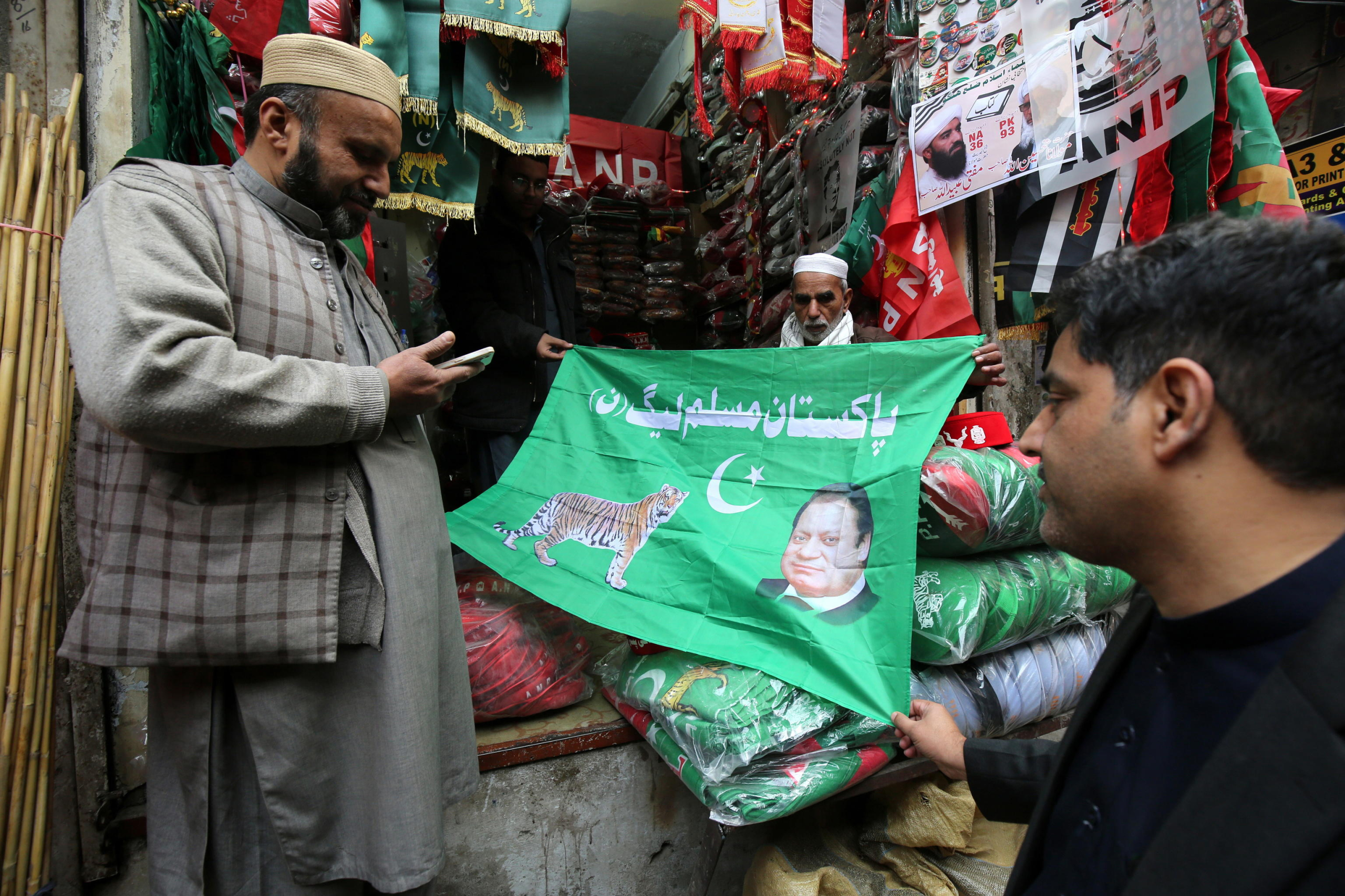 epaselect epa11067345 Vendors sell flags of Pakistan Muslim League Nawaz (PML-N) depicting images of the party's leader former Prime Minister Nawaz Sharif as the country gears up for general elections, in Peshawar, Pakistan, 10 January 2024. General elections are set to be held in Pakistan on 08 February 2024.  EPA/BILAWAL ARBAB