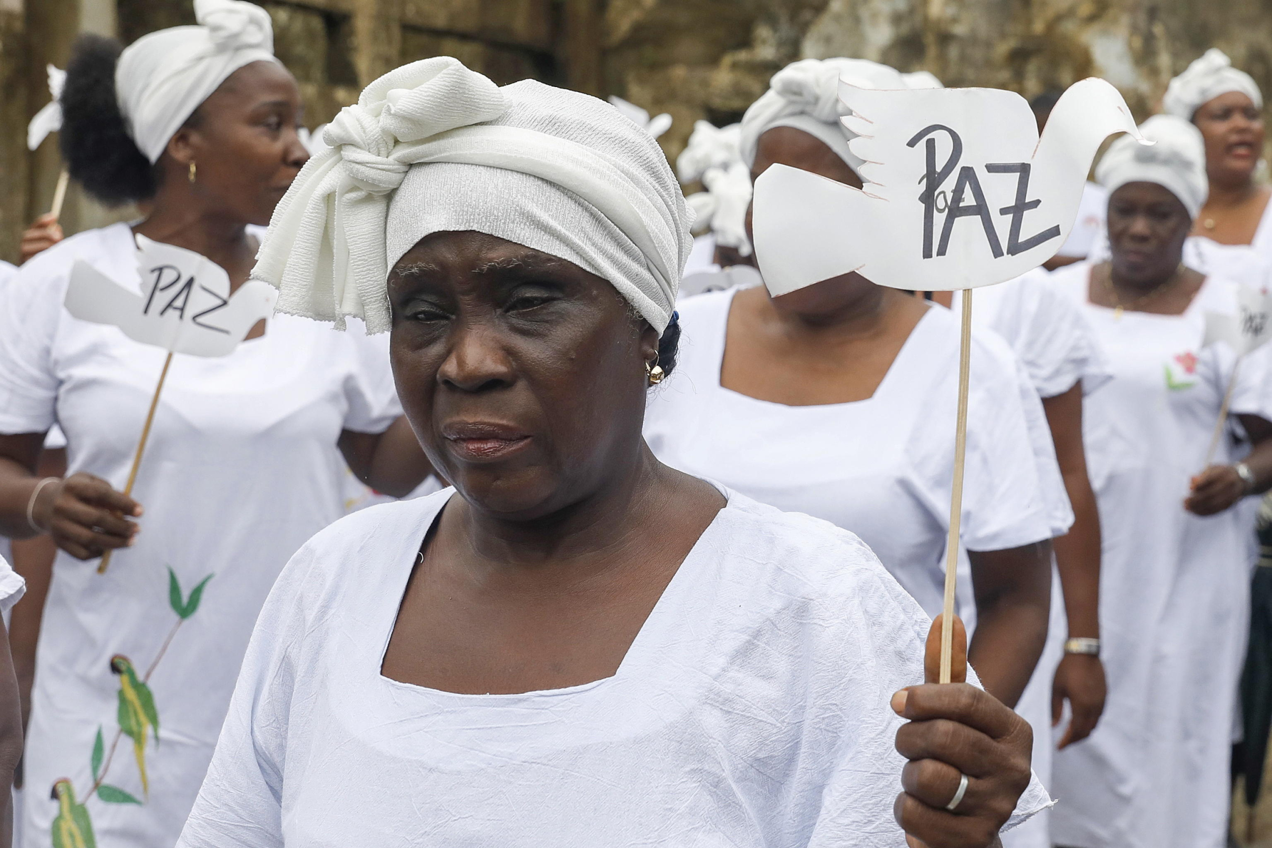 epa11315506 A cantadora de Pogue holds a sign that reads 'Peace' during the commemoration of the 22nd anniversary of the Bojayá massacre, in Bojaya, Colombia, 02 May 2024. The Afro-descendant and indigenous communities of Bojaya, a municipality in the Colombian department of Choco, held a commemoration ceremony for the relatives and friends who died in the massacre that in which more than a hundred people were killed, 22 years ago.  EPA/Luis Eduardo Noriega A.