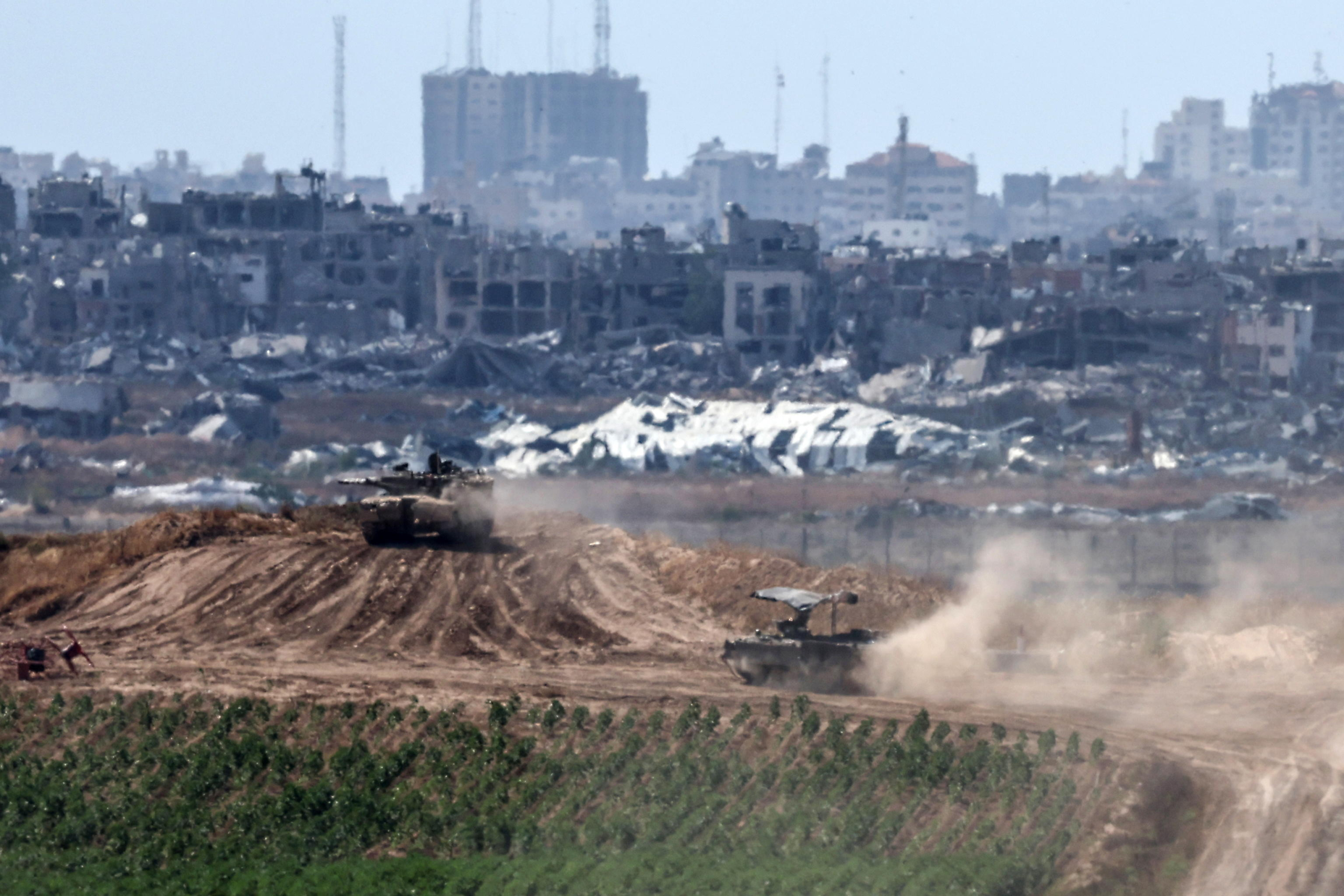 epa11337107 Israeli tanks maneuver along the border with the Gaza Strip, near the Palestinian city of Jabalia (background), as seen from the Israeli side of the border, southern Israel, 13 May 2024. More than 34,900 Palestinians and over 1,455 Israelis have been killed, according to the Palestinian Health Ministry and the Israel Defense Forces (IDF), since Hamas militants launched an attack against Israel from the Gaza Strip on 07 October 2023, and the Israeli operations in Gaza and the West Bank which followed it  EPA/ATEF SAFADI