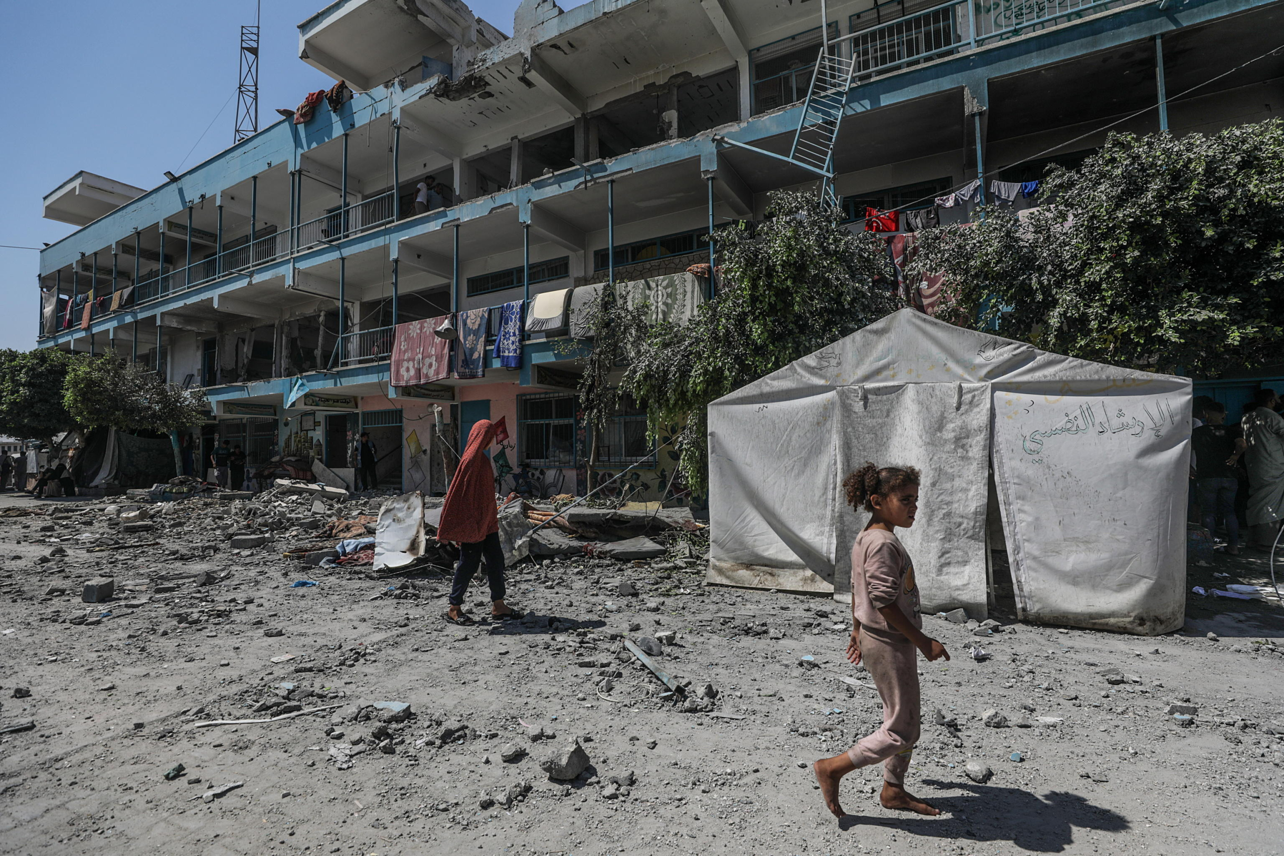 epa11392940 Internally displaced Palestinians walk in the courtyard of a destroyed UNRWA school following an Israeli air strike in Al Nusairat refugee camp in the central Gaza Strip on, 06 June 2024. According to the Palestinian News Agency Wafa, at least 32 people  were killed and dozens others were injured on early 06 June following an Israeli strike on a UNRWA school sheltering displaced Palestinians, located in the Nuseirat refugee camp in the central Gaza strip. The Israeli army said that it had 