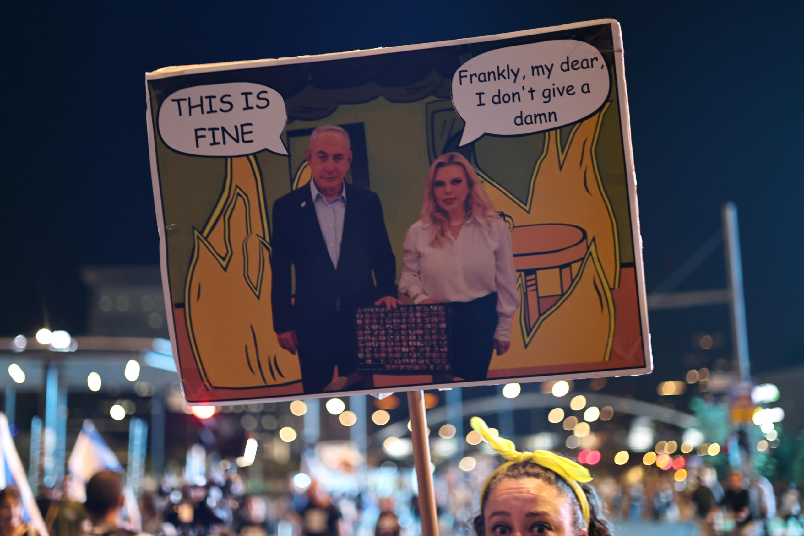 epa11445951 An Israeli protester holds up a banner depicting Prime Minister Benjamin Netanyahu (L) and his wife, Sara Netanyahu (R), during an anti-government demonstration calling for immediate elections, the resignation of Prime Minister Netanyahu's government and the release of the hostages, near the Kirya military headquarters in Tel Aviv, Israel, 29 June 2024.  EPA/ATEF SAFADI