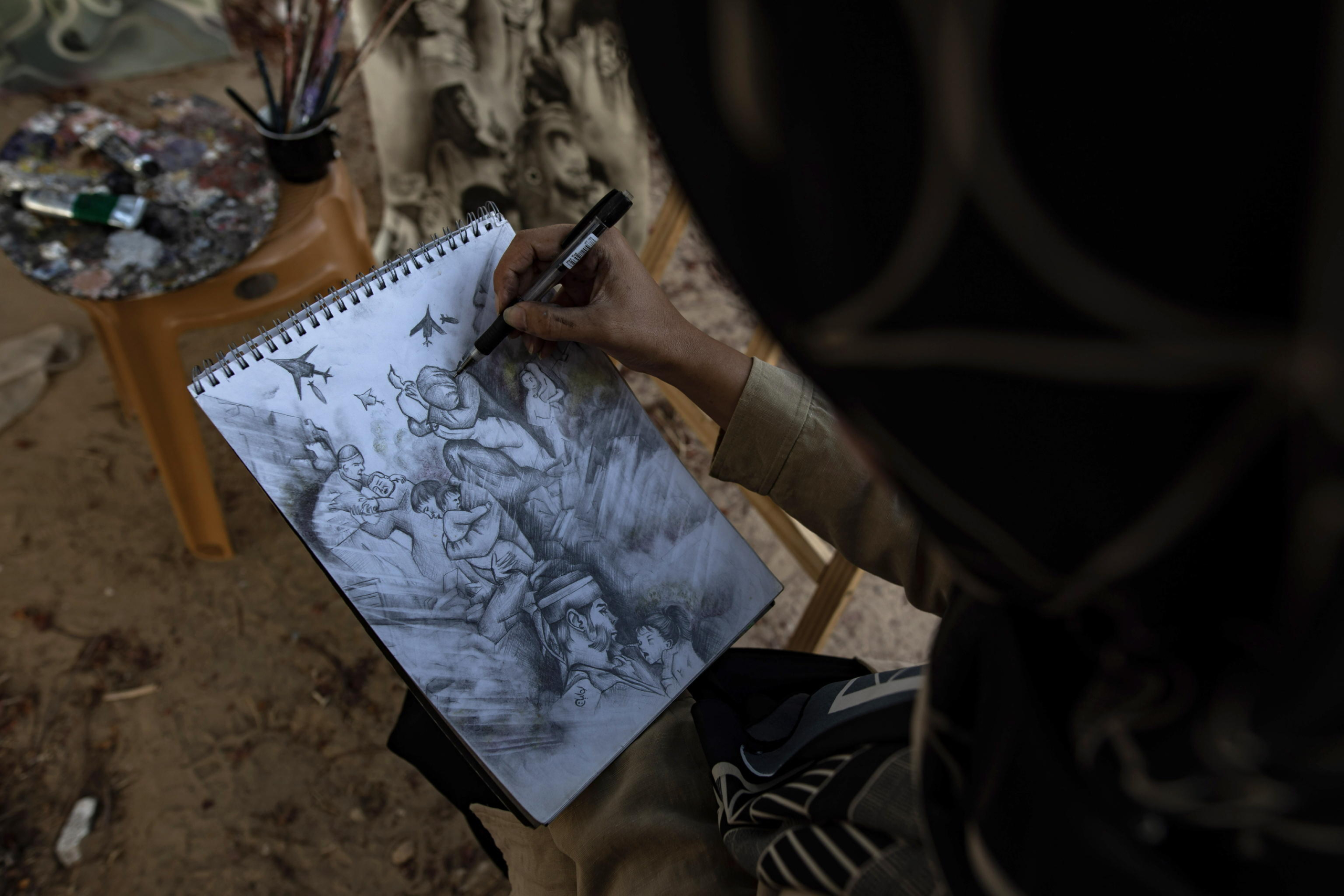 epa11480497 Visual artist Ilham Al-Astal, 28, a displaced Palestinian from Khan Yunis camp, sketching on a paper near her destroyed home, in Khan Yunis, southern Gaza Strip, 15 July 2024. Through art, Ilham depicts the suffering of displaced people, highlighting events and scenes from the ongoing conflict in Gaza. Since 07 October 2023, up to 1.7 million people, or more than 75 percent of the population, have been displaced throughout the Gaza Strip, some more than once, in search of safety, according to the United Nations Relief and Works Agency for Palestine Refugees in the Near East (UNRWA), which added that the Palestinian enclave is 'on the brink of famine', with 1.1 million people (half of its population) 'experiencing catastrophic food insecurity' due to the conflict and restrictions on humanitarian access.  EPA/HAITHAM IMAD