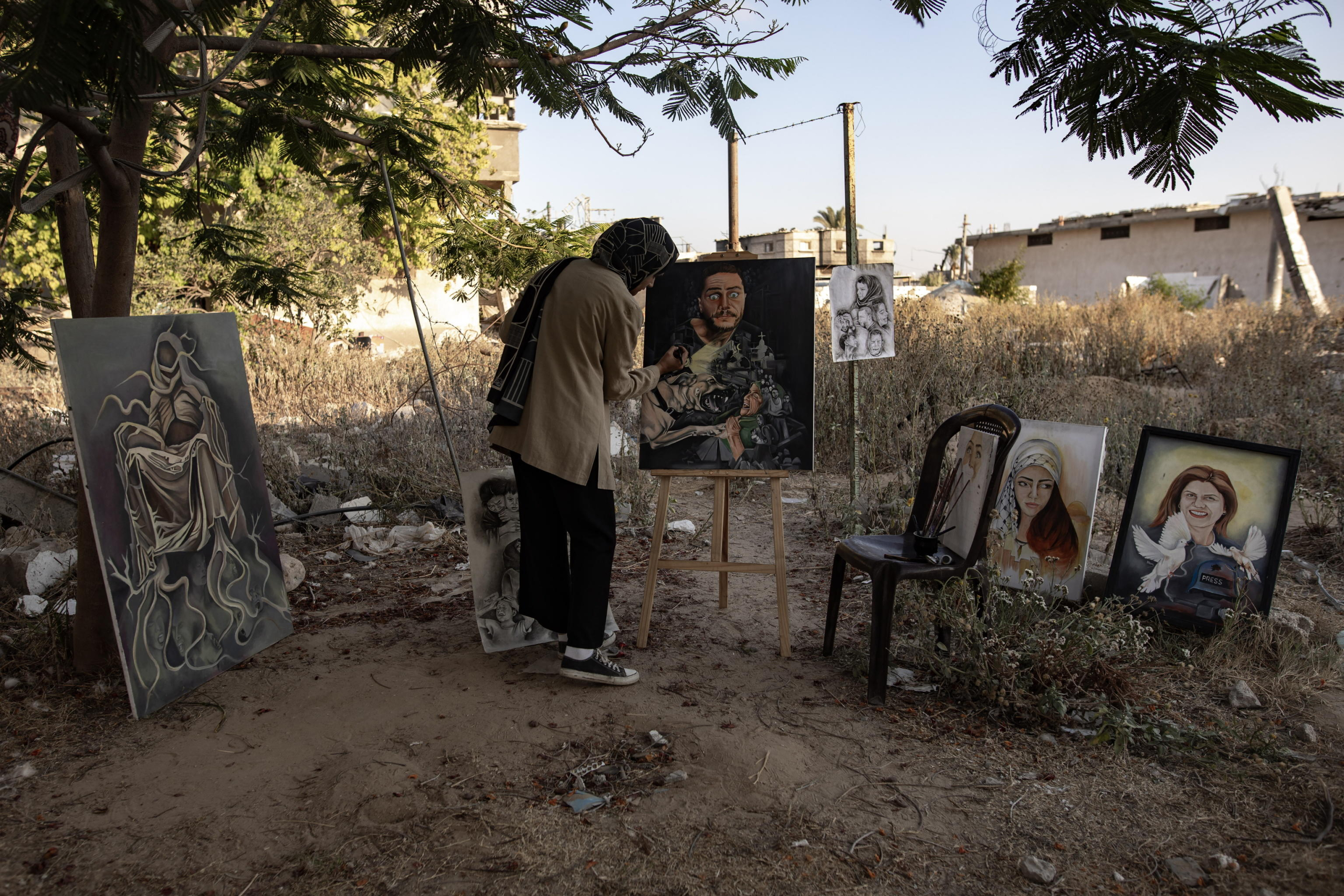epa11480500 Visual artist Ilham Al-Astal, 28, a displaced Palestinian from Khan Yunis camp, paints near her destroyed home, in Khan Yunis, southern Gaza Strip, 15 July 2024. Through art, Ilham depicts the suffering of displaced people, highlighting events and scenes from the ongoing conflict in Gaza. Since 07 October 2023, up to 1.7 million people, or more than 75 percent of the population, have been displaced throughout the Gaza Strip, some more than once, in search of safety, according to the United Nations Relief and Works Agency for Palestine Refugees in the Near East (UNRWA), which added that the Palestinian enclave is 'on the brink of famine', with 1.1 million people (half of its population) 'experiencing catastrophic food insecurity' due to the conflict and restrictions on humanitarian access.  EPA/HAITHAM IMAD