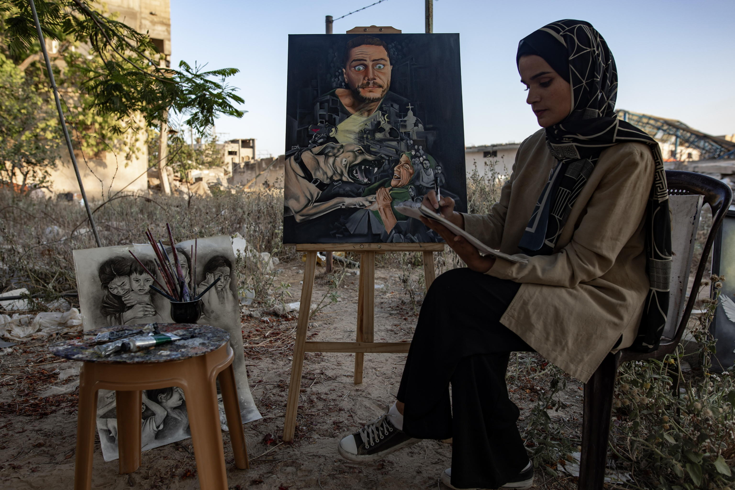 epaselect epa11480499 Visual artist Ilham Al-Astal, 28, a displaced Palestinian from Khan Yunis camp, paints near her destroyed home, in Khan Yunis, southern Gaza Strip, 15 July 2024. Through art, Ilham depicts the suffering of displaced people, highlighting events and scenes from the ongoing conflict in Gaza. Since 07 October 2023, up to 1.7 million people, or more than 75 percent of the population, have been displaced throughout the Gaza Strip, some more than once, in search of safety, according to the United Nations Relief and Works Agency for Palestine Refugees in the Near East (UNRWA), which added that the Palestinian enclave is 'on the brink of famine', with 1.1 million people (half of its population) 'experiencing catastrophic food insecurity' due to the conflict and restrictions on humanitarian access.  EPA/HAITHAM IMAD
