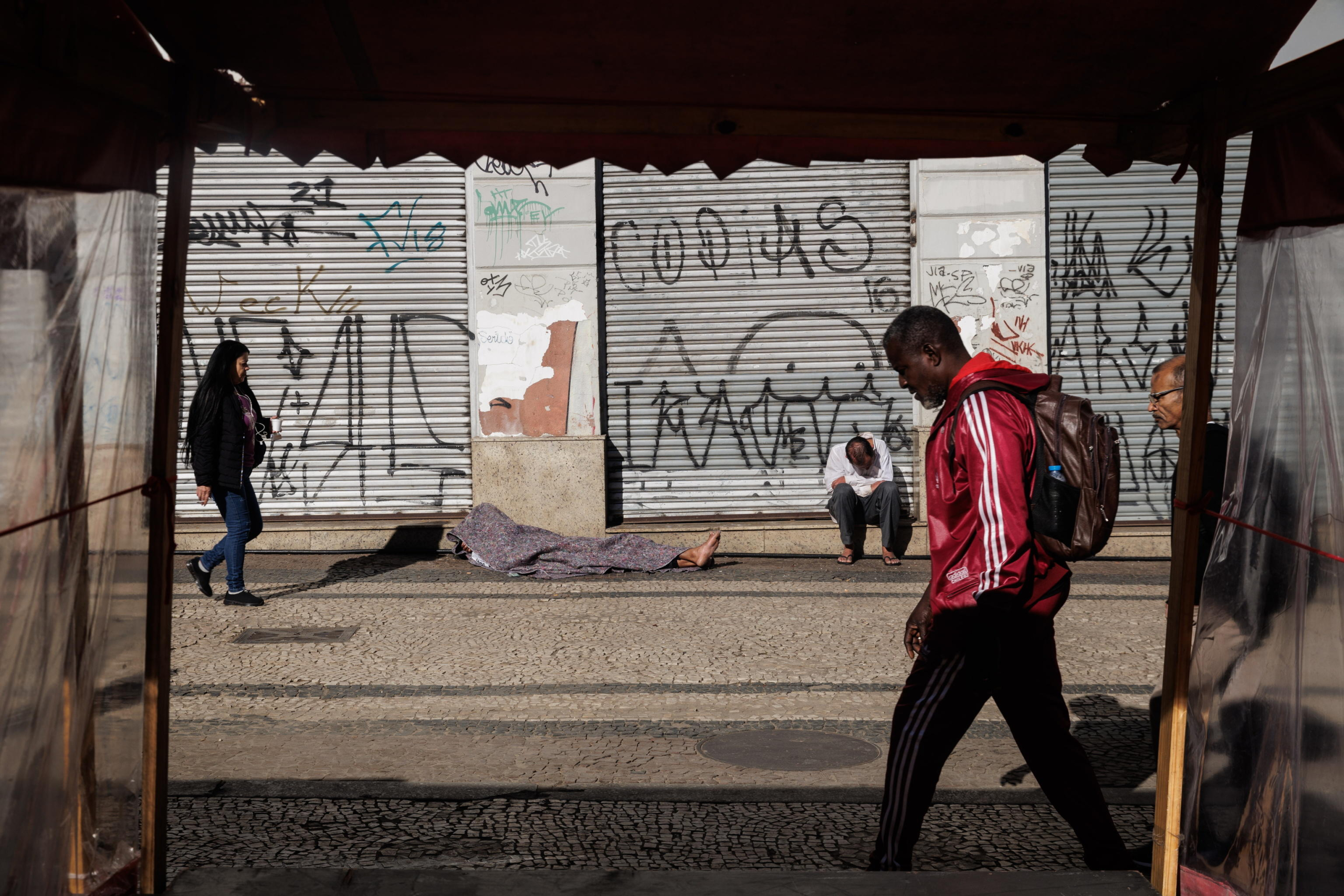 epa11494171 Pedestrians walk by homeless people sleeping in the city center in Sao Paulo, Brazil, 24 July 2024. According to a report released on 24 July 2024 by five United Nations agencies, hunger levels remained high in 2023 for the third consecutive year, with approximately 733 million people worldwide suffering from chronic undernourishment.  EPA/Isaac Fontana