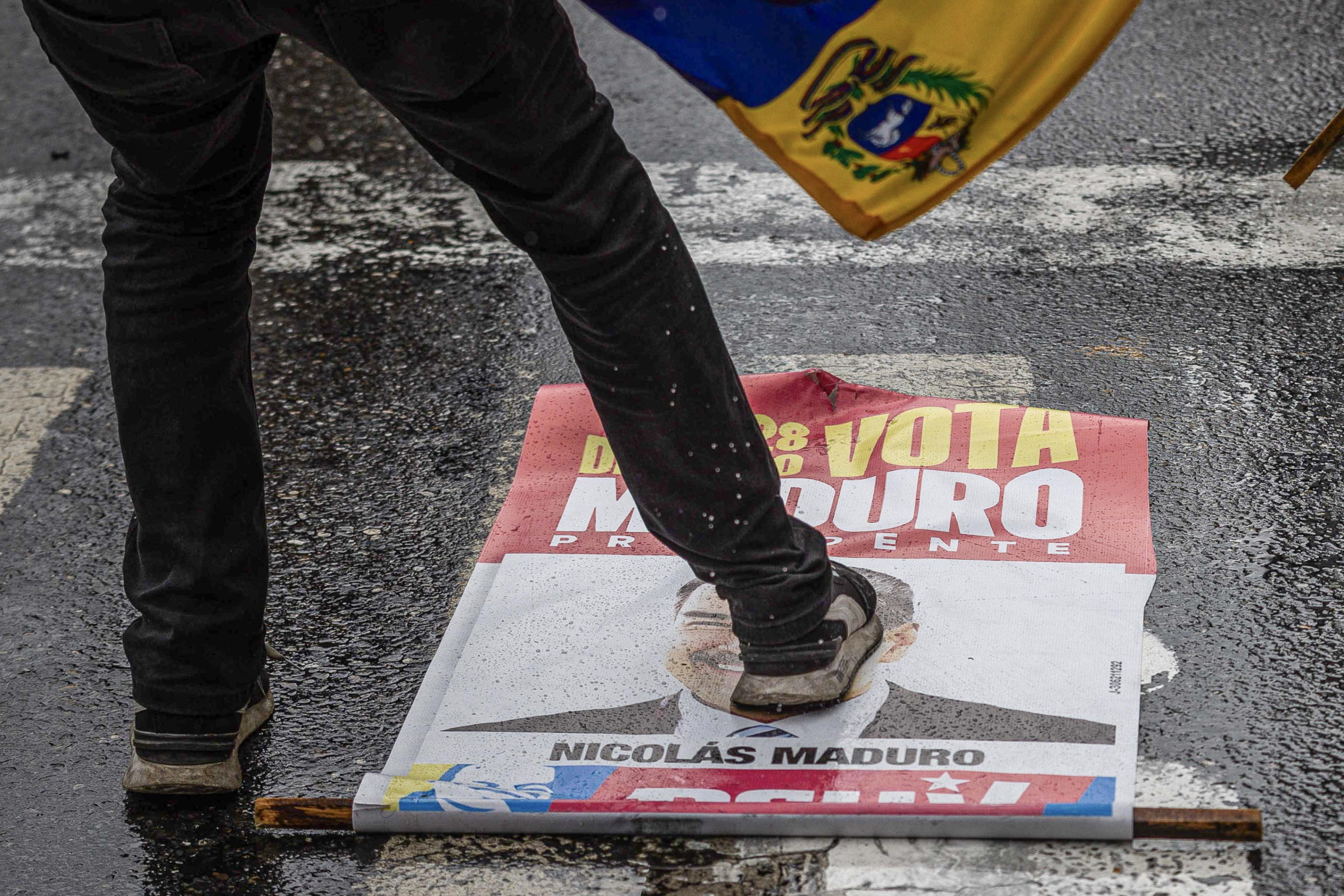 epa11507660 A person steps on a poster with the image of Venezuela's President Nicolas Maduro during a protest against the results of the presidential elections in Caracas, Venezuela, 29 July 2024. Protests are taking place in Caracas after the National Electoral Council (CNE) proclaimed that Nicolas Maduro was re-elected president of Venezuela, following elections held on 28 July.  EPA/Henry Chirinos