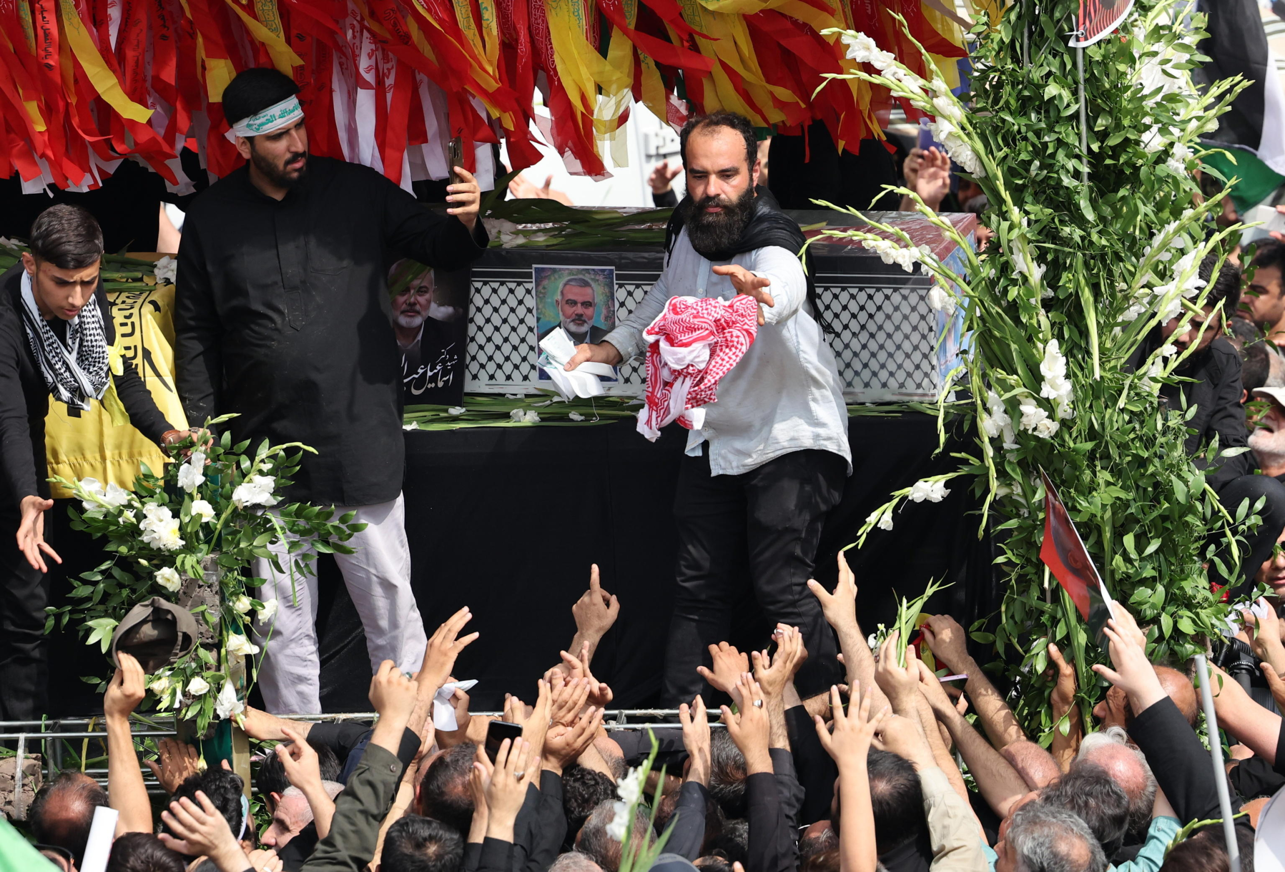 epa11514374 People gather around a truck carrying the coffins of Hamas late political leader Ismail Haniyeh and his bodyguard, during a funeral procession in Tehran, Iran, 01 August 2024. Haniyeh and one of his bodyguards were targeted and killed in Tehran on 31 July 2024, the Iranian Revolutionary Guard Corps (IRGC) confirmed.  EPA/ABEDIN TAHERKENAREH