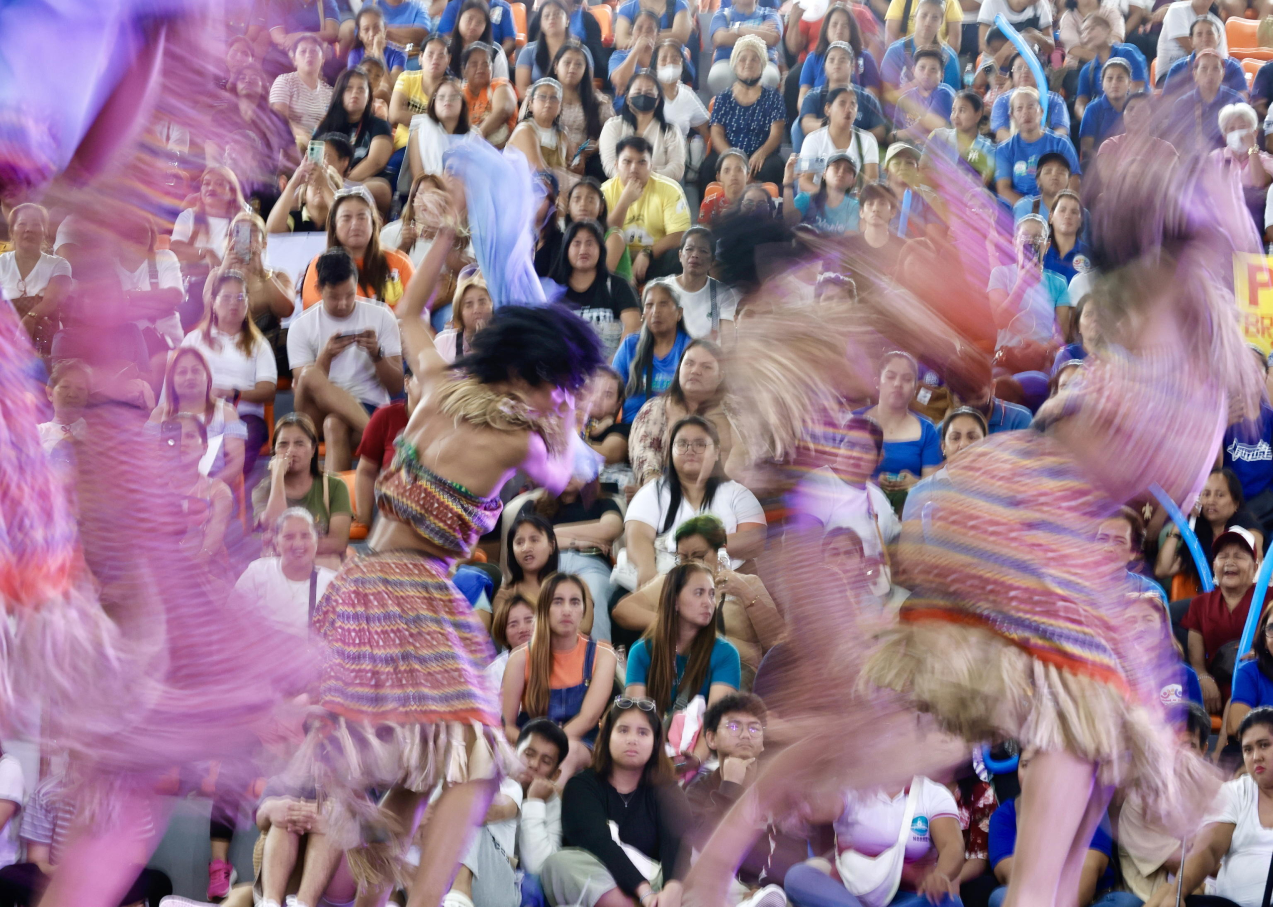 epa11529286 A slow shutter speed photo shows Filipino teens, wearing traditional costumes made from dried water hyacinth stalks, performing during the Water Lily Festival in Las Pinas city, Metro Manila, Philippines, 06 August 2024. The annual Water Lily Festival in Las Pinas city was declared by the Villar Foundation to highlight the transformation of water lilies from aquatic nuisances to valuable resources. Through the 'Water Lily Weaving Project', the foundation turns these plants into handicrafts, creating livelihoods and aiding community rehabilitation. During the festival, villagers parade in traditional costumes made from dried water lilies, showcasing the project's success and promoting the benefits of water lily-based livelihoods for local residents.  EPA/FRANCIS R. MALASIG
