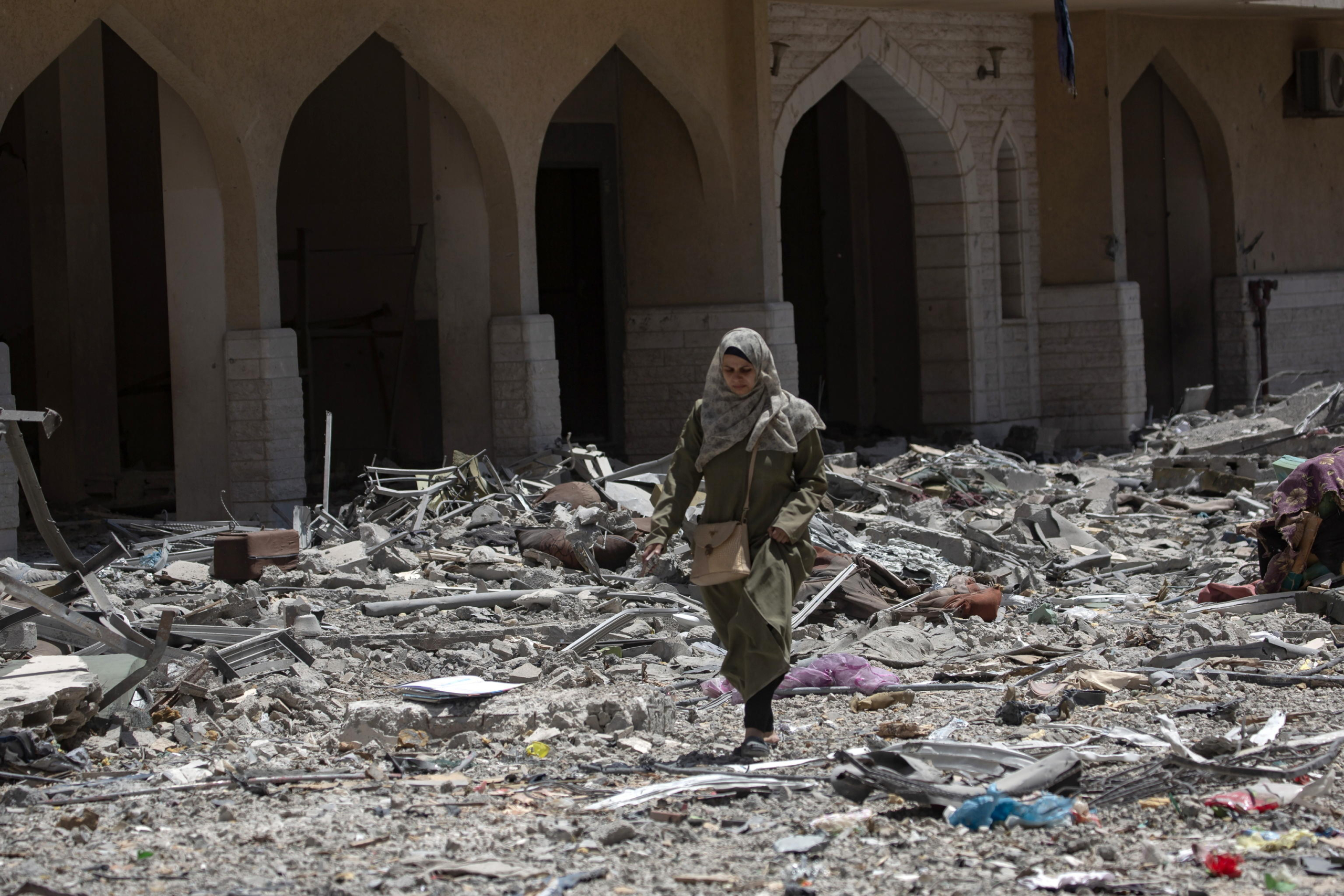 epa11562791 A woman walks among debris as Palestinians inspect the damage after the withdrawal of Israeli forces from Hamad City in Khan Yunis, southern Gaza Strip, 24 August 2024. More than 40,000 Palestinians and over 1,400 Israelis have been killed, according to the Palestinian Health Ministry and the Israel Defense Forces (IDF), since Hamas militants launched an attack against Israel from the Gaza Strip on 07 October 2023, and the Israeli operations in Gaza and the West Bank which followed it.  EPA/HAITHAM IMAD