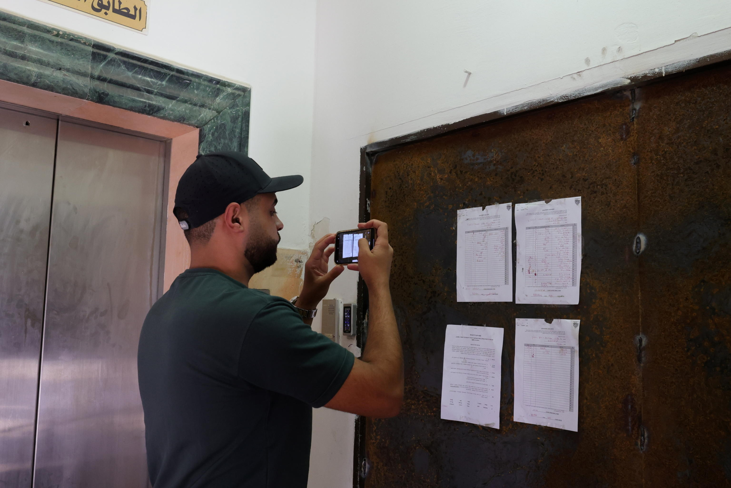 epa11618527 A man stands in front of a closure order by the Israeli military hanging on the main entrance to the Al Jazeera office in the West Bank city of Ramallah, 22 September 2024. Armed Israeli soldiers stormed into Al Jazeera's offices in the West Bank city of Ramallah on 22 September, ordering staff to leave and imposing a 45-day closure on the network, the news broadcaster said. The raid came just months after Israel banned Al Jazeera from operating inside Israel. Israel is yet to comment on the operation.  EPA/ALAA BADARNEH