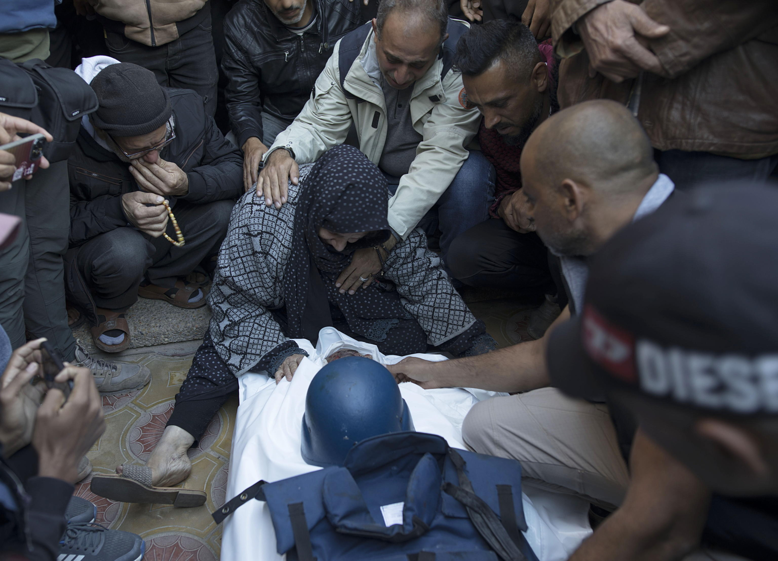 epaselect epa11031999 Relatives of Palestinian journalist Samer Abu Daqqa, cameraman for Al Jazeera, who was killed during Israeli air strikes in the southern Gaza Strip, with press crews next to his wrapped body, outside Nasser Hospital in Khan Yunis, southern Gaza Strip, 16 December 2023. More than 18,000 Palestinians and at least 1,200 Israelis have been killed, according to the Palestinian Health Ministry and the Israel Defense Forces (IDF), since Hamas militants launched an attack against Israel from the Gaza Strip on 07 October, and the Israeli operations in Gaza and the West Bank which followed it.  EPA/HAITHAM IMAD