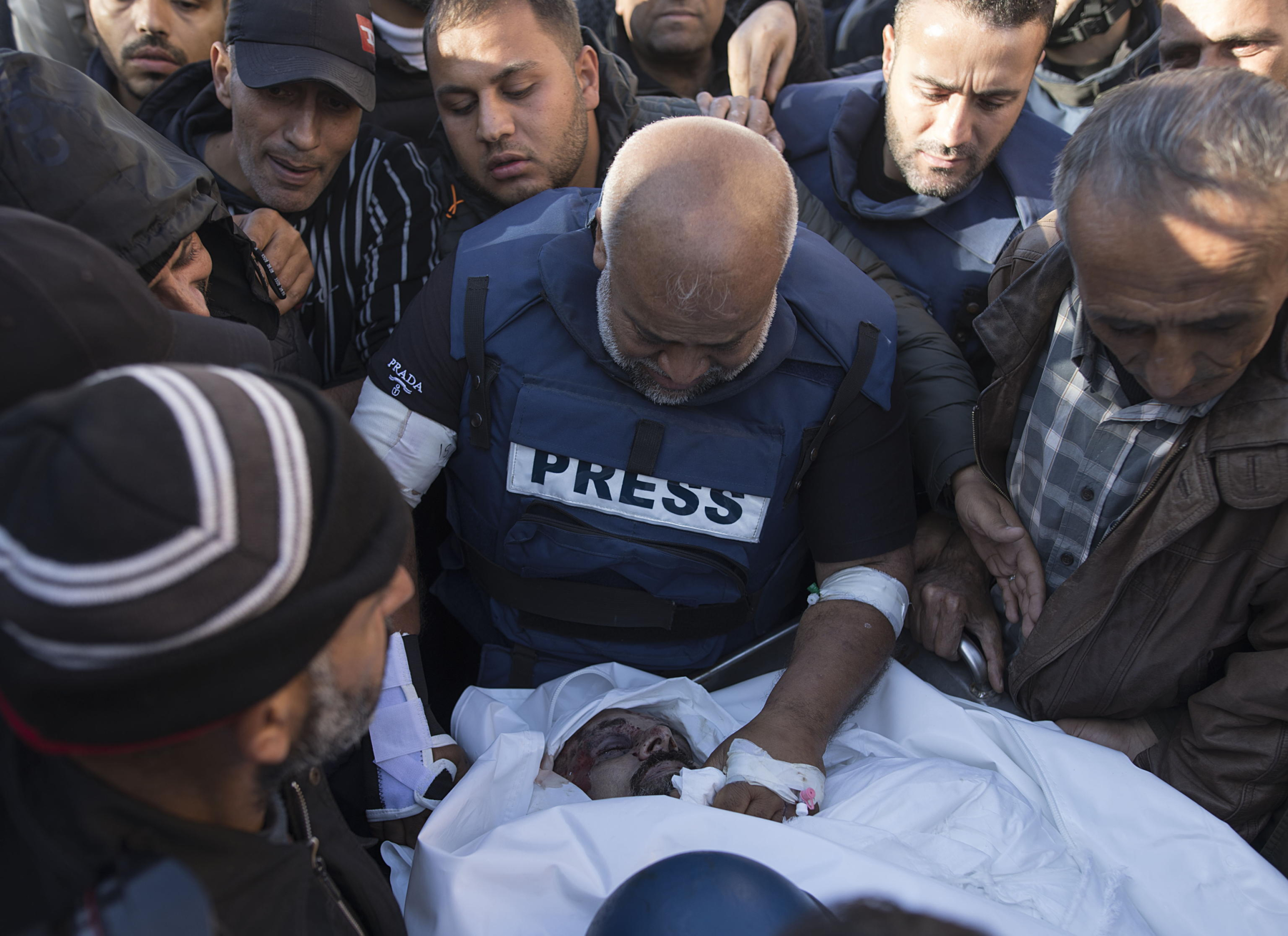 epa11032005 Relatives of Palestinian journalist Samer Abu Daqqa, cameraman for Al Jazeera, who was killed during Israeli air strikes in the southern Gaza Strip, with press crews next to his wrapped body, outside Nasser Hospital in Khan Yunis, southern Gaza Strip, 16 December 2023. More than 18,000 Palestinians and at least 1,200 Israelis have been killed, according to the Palestinian Health Ministry and the Israel Defense Forces (IDF), since Hamas militants launched an attack against Israel from the Gaza Strip on 07 October, and the Israeli operations in Gaza and the West Bank which followed it.  EPA/HAITHAM IMAD