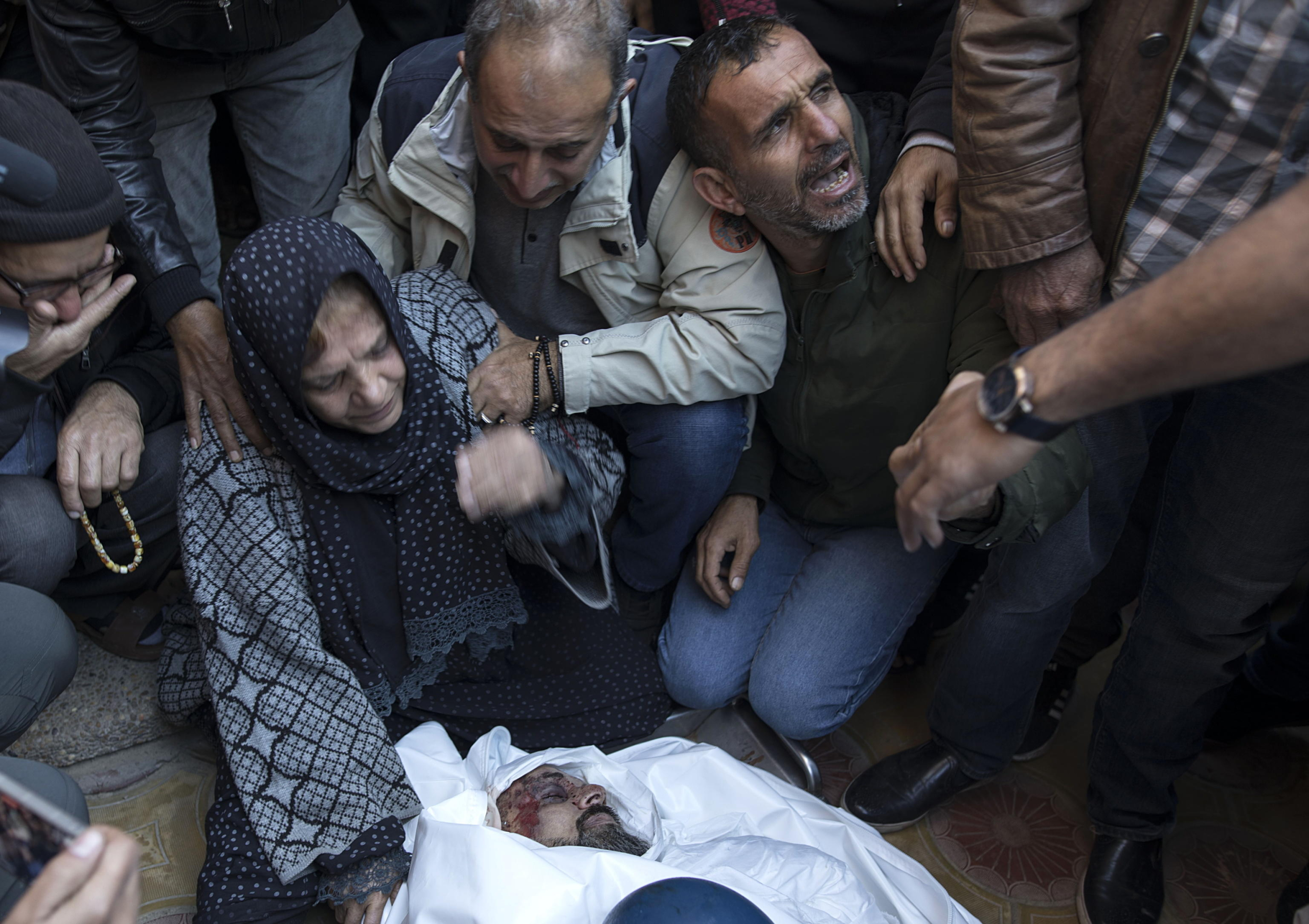 epa11032002 Relatives of Palestinian journalist Samer Abu Daqqa, cameraman for Al Jazeera, who was killed during Israeli air strikes in the southern Gaza Strip, with press crews next to his wrapped body, outside Nasser Hospital in Khan Yunis, southern Gaza Strip, 16 December 2023. More than 18,000 Palestinians and at least 1,200 Israelis have been killed, according to the Palestinian Health Ministry and the Israel Defense Forces (IDF), since Hamas militants launched an attack against Israel from the Gaza Strip on 07 October, and the Israeli operations in Gaza and the West Bank which followed it.  EPA/HAITHAM IMAD