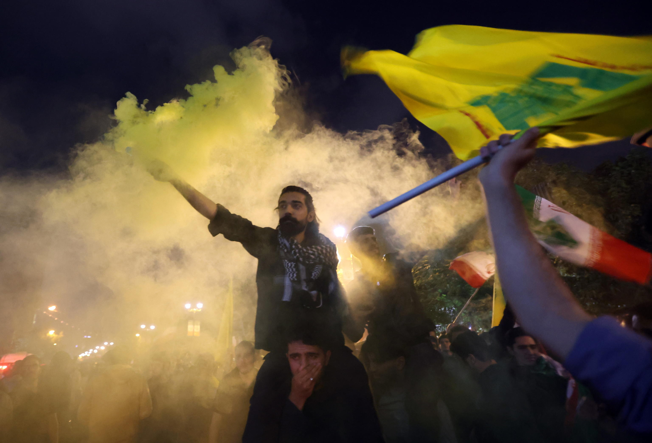 epa11636790 Iranians hold Iranian and Hezbollah flags as they celebrate after Iran launched a missile attack on Israel, next to the British embassy, in Tehran, Iran, 01 October 2024. Iran has launched dozens of missiles directed at Israel on 01 October 2024, state media reported quoting the Islamic Revolutionary Guard Corps (IRGC). The attack was a 'retaliation for different assassinations' carried out by Israel and 'the crimes in Palestine and Lebanon', IRGC said.  EPA/ABEDIN TAHERKENAREH