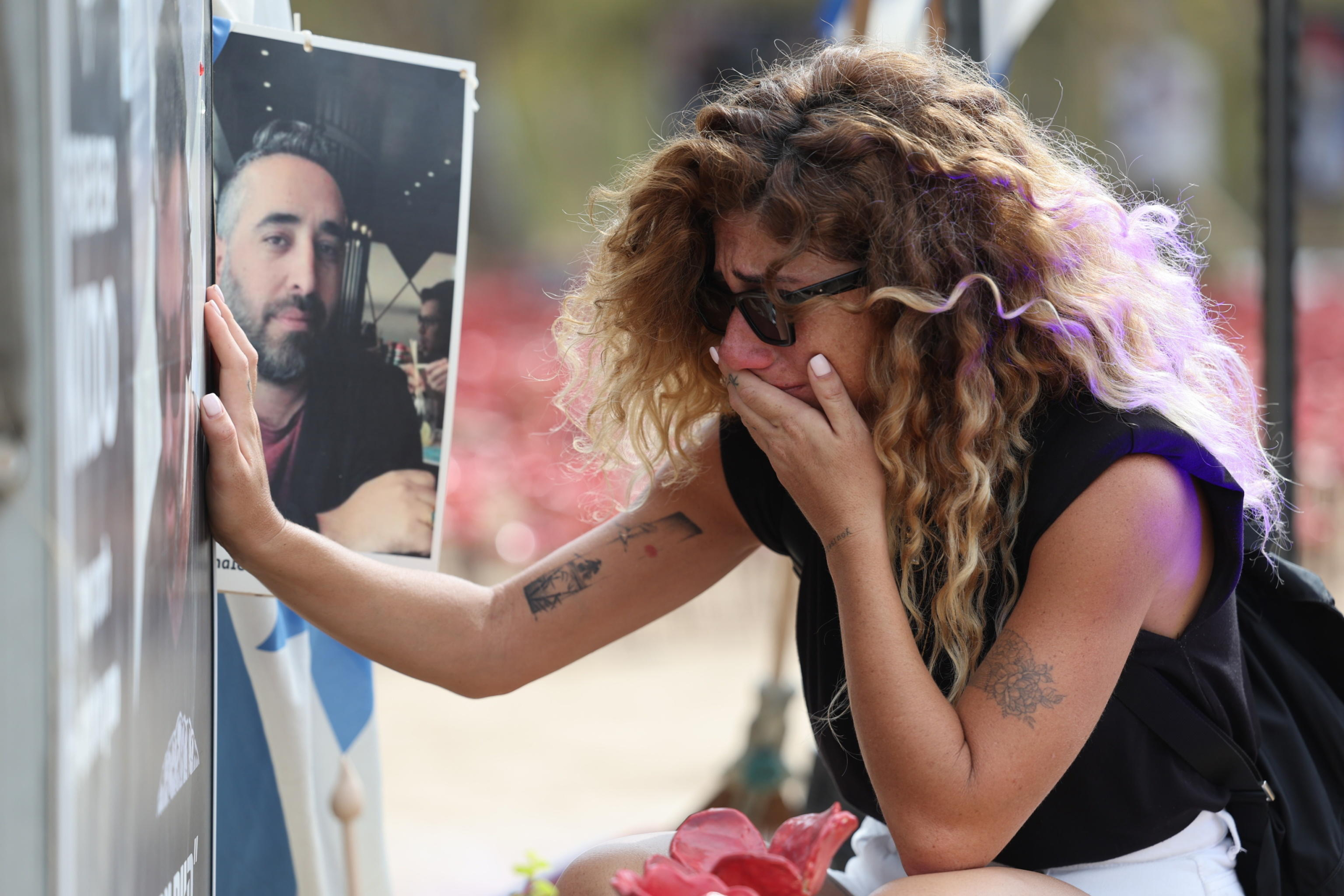 epa11645352 A woman reacts next to a portrait at the memorial site for the victims of the 07 October 2023 Supernova music festival attack, near Kibbutz Re'im, close to the border with the Gaza Strip, in southern Israel, 06 October 2024. According to Israeli police, 364 Israelis were killed at the SuperNova music festival on 07 October 2023 by Hamas militants that stormed the area during a surprise attack launched from the Gaza Strip. Upcoming 07 October 2024, marks one year since the Palestinian militant group Hamas launched a surprise attack on Israel, killing 1,200, and one year since Israel began its war on Gaza, killing more than 41,000 and destroying the Palestinian enclave. On 07 October 2023, armed Palestinian groups led by Hamas launched a deadly assault on Israel, with rocket launches and thousands of militants breaching the Gaza-Israel security barrier to attack Israeli communities and military bases near Gaza and central Israel and taking dozens of hostages. Israel, then, officially declared a state of war against Hamas, setting the stage for a major military response in the strip.  EPA/ABIR SULTAN