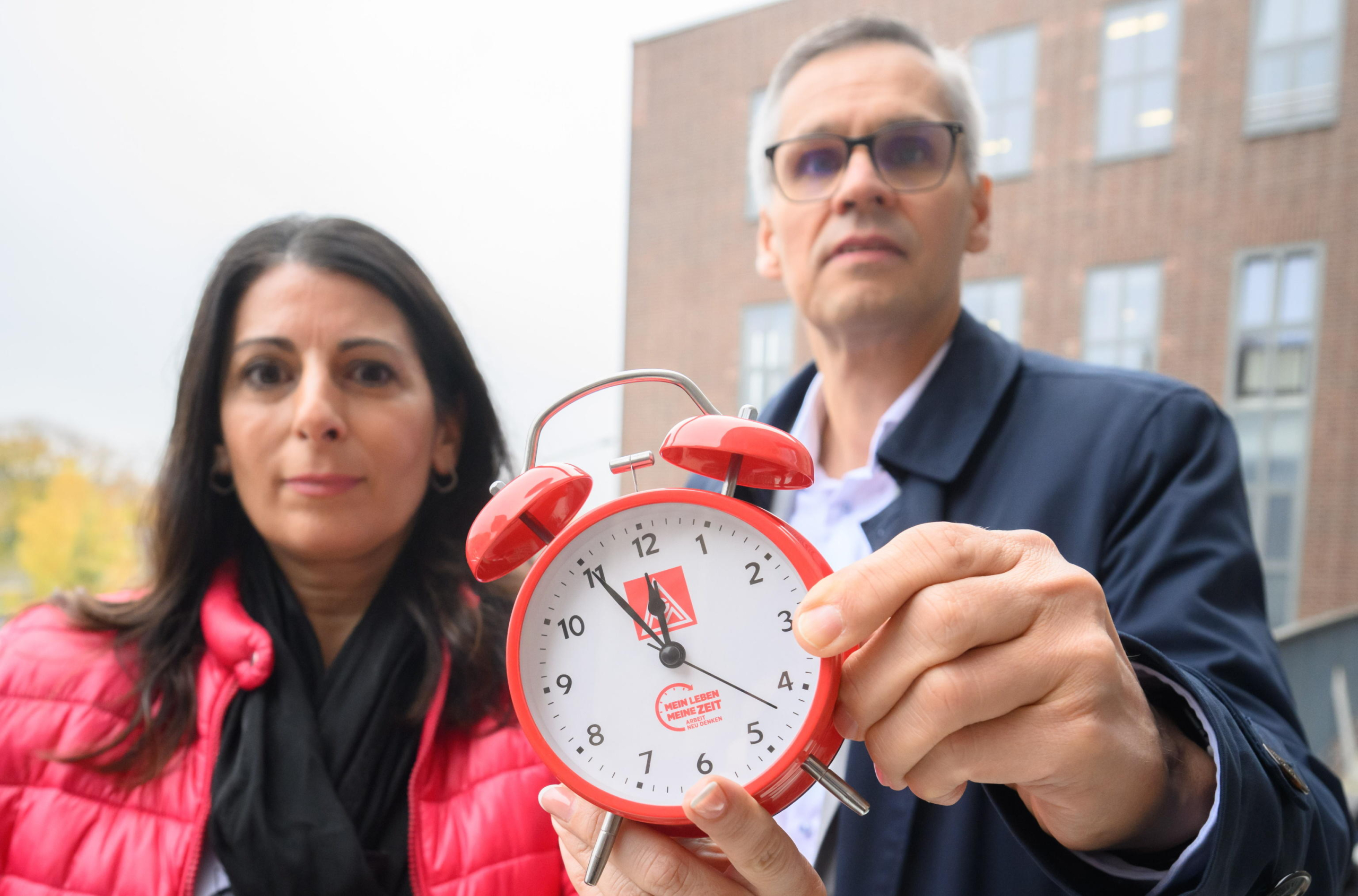 epa11688783 Daniela Cavallo (L), Chairwoman of the General and Group Works Council of Volkswagen AG, and Thorsten Groeger (R), IG Metall negotiator, hold an alarm clock as they participate in an informational event organized by the General Works Council of Volkswagen AG at the company's main plant in Wolfsburg, Germany, 28 October 204. The event will address topics such as wage reductions, possible plant shutdowns, and workforce layoffs.  EPA/JULIAN STRATENSCHULTE / POOL