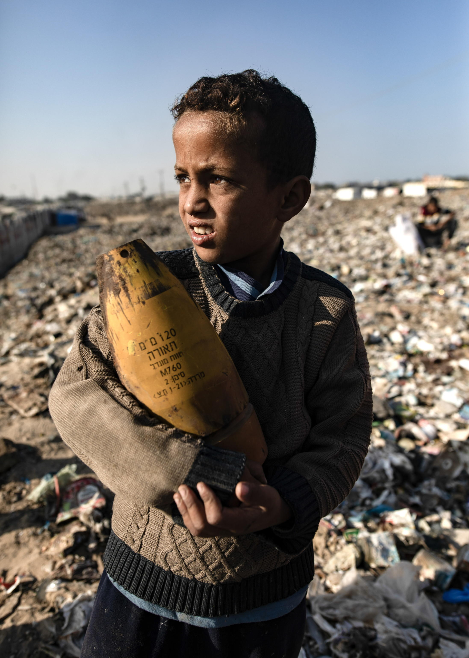 epaselect epa11700530 A Palestinian boy holds an Israeli artillery shell found while sorting through the garbage at a landfill, amid a shortage of cooking gas and fuel, at the Khan Younis refugee camp, in the southern Gaza Strip, 04 November 2024. A United Nations Office for the Coordination of Humanitarian Affairs (OCHA) assessment carried out across some IDP camps in Gaza in May 2024 pointed to 'makeshift dwellings being made of blankets, nylon, and foraged materials. With no electricity, and cooking gas and wood being too expensive, families were resorting to burning trash and plastic to cook. According to the UN, at least 1.9 million people across the Gaza Strip are internally displaced. Since October 2023, only about 11 percent of the Gaza Strip has not been placed under Israeli-issued evacuation orders, the UN aid coordination office OCHA said.  EPA/HAITHAM IMAD