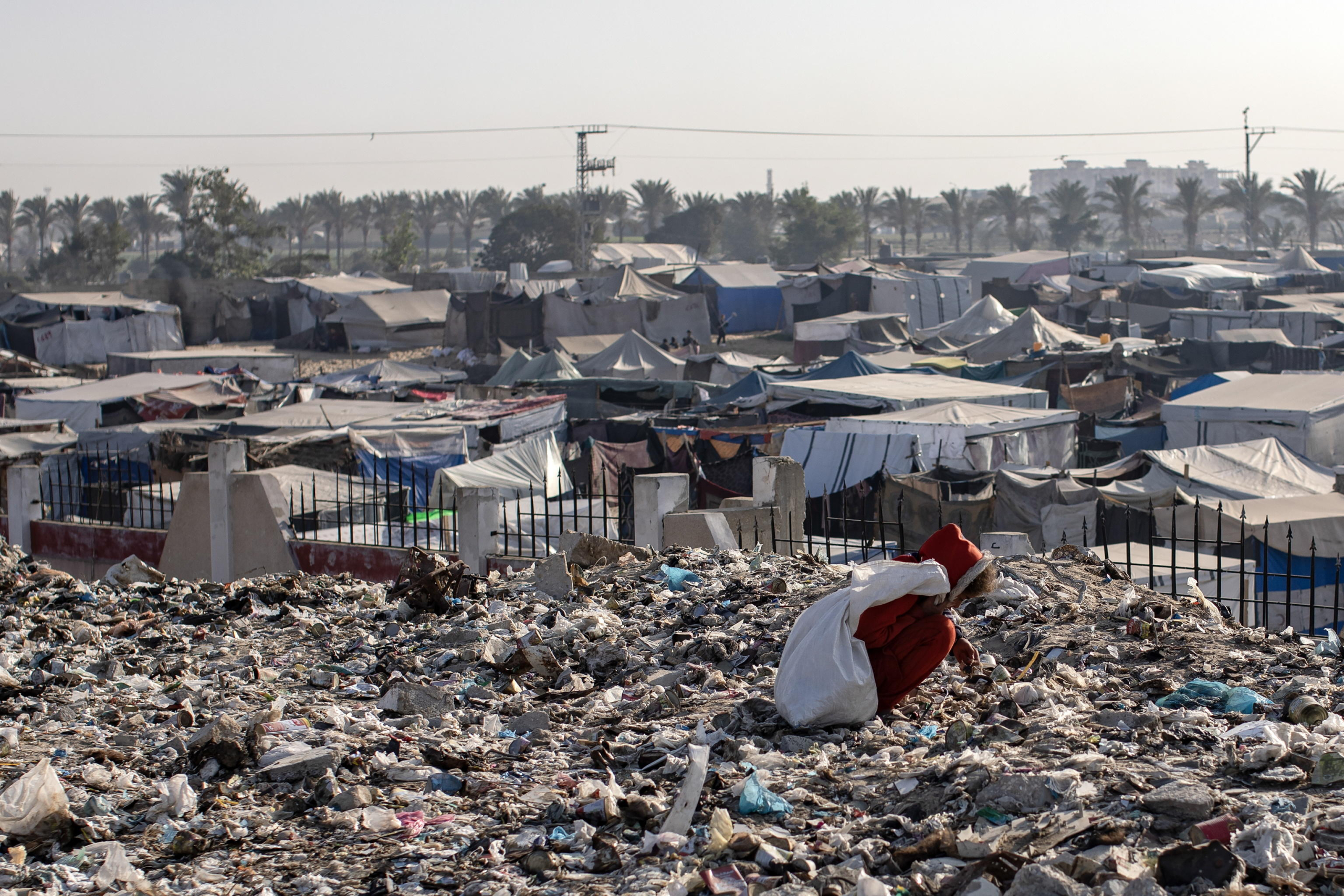 epa11700504 A Palestinian child sorts through garbage while collecting plastic from a landfill, amid a shortage of cooking gas and fuel, at the Khan Younis refugee camp, in the southern Gaza Strip, 04 November 2024. A United Nations Office for the Coordination of Humanitarian Affairs (OCHA) assessment carried out across some IDP camps in Gaza in May 2024 pointed to 'makeshift dwellings being made of blankets, nylon, and foraged materials. With no electricity, and cooking gas and wood being too expensive, families were resorting to burning trash and plastic to cook. According to the UN, at least 1.9 million people across the Gaza Strip are internally displaced. Since October 2023, only about 11 percent of the Gaza Strip has not been placed under Israeli-issued evacuation orders, the UN aid coordination office OCHA said.  EPA/HAITHAM IMAD