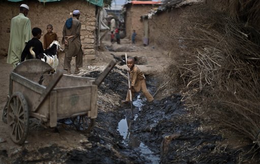 Un bambino rifugiato afghano scava un canale nella periferia di Islamabad