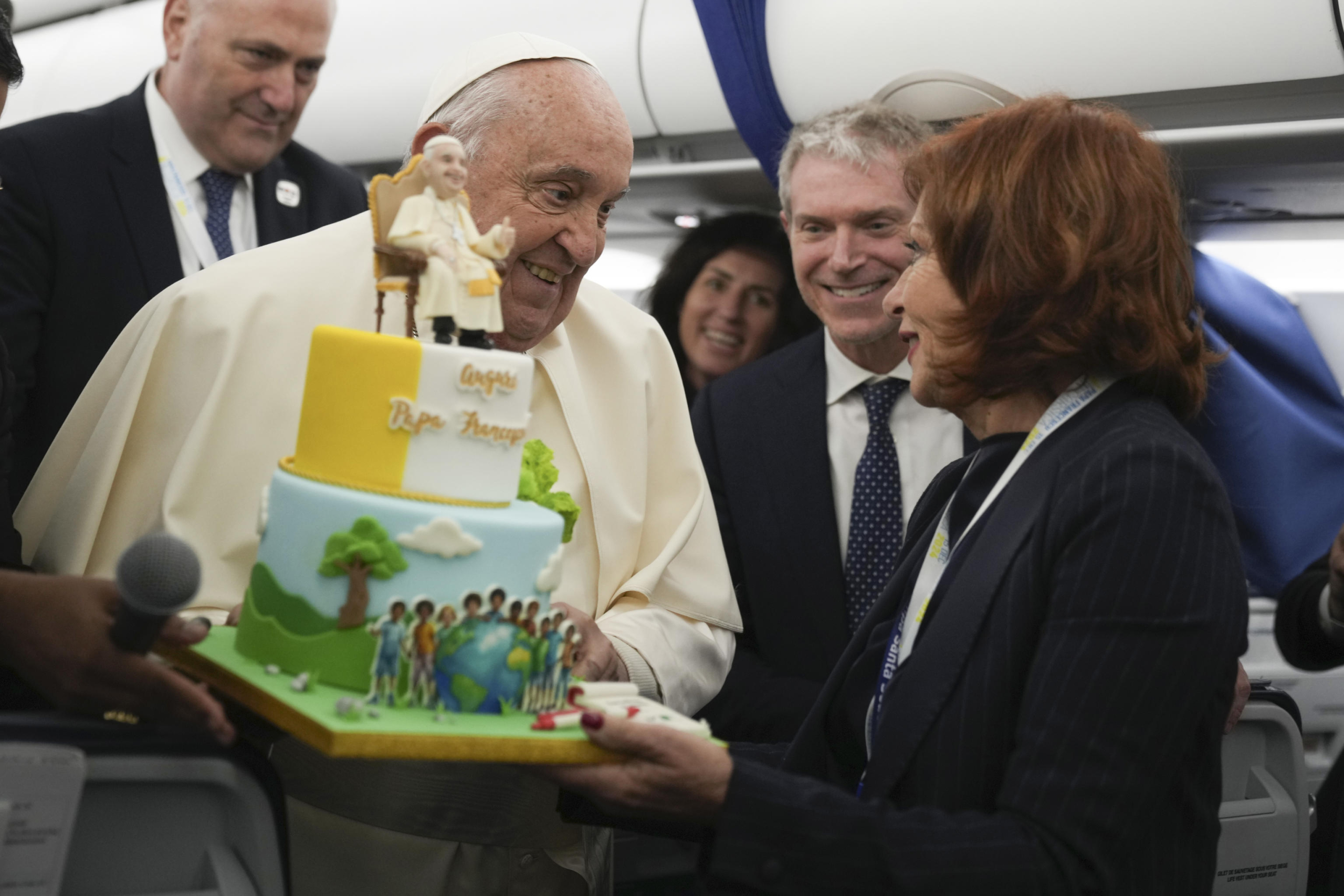 Pope Francis is presented with a cake by Valentina Alazraki, correspondent for TeleVisa Univision, to celebrate his upcoming Dec. 17, 88th birthday, on the flight back to Rome at the end of his one-day visit to Ajaccio in the French island of Corsica, Sunday, Dec. 15, 2024. ANSA/AP Photo/Alessandra Tarantino, Pool