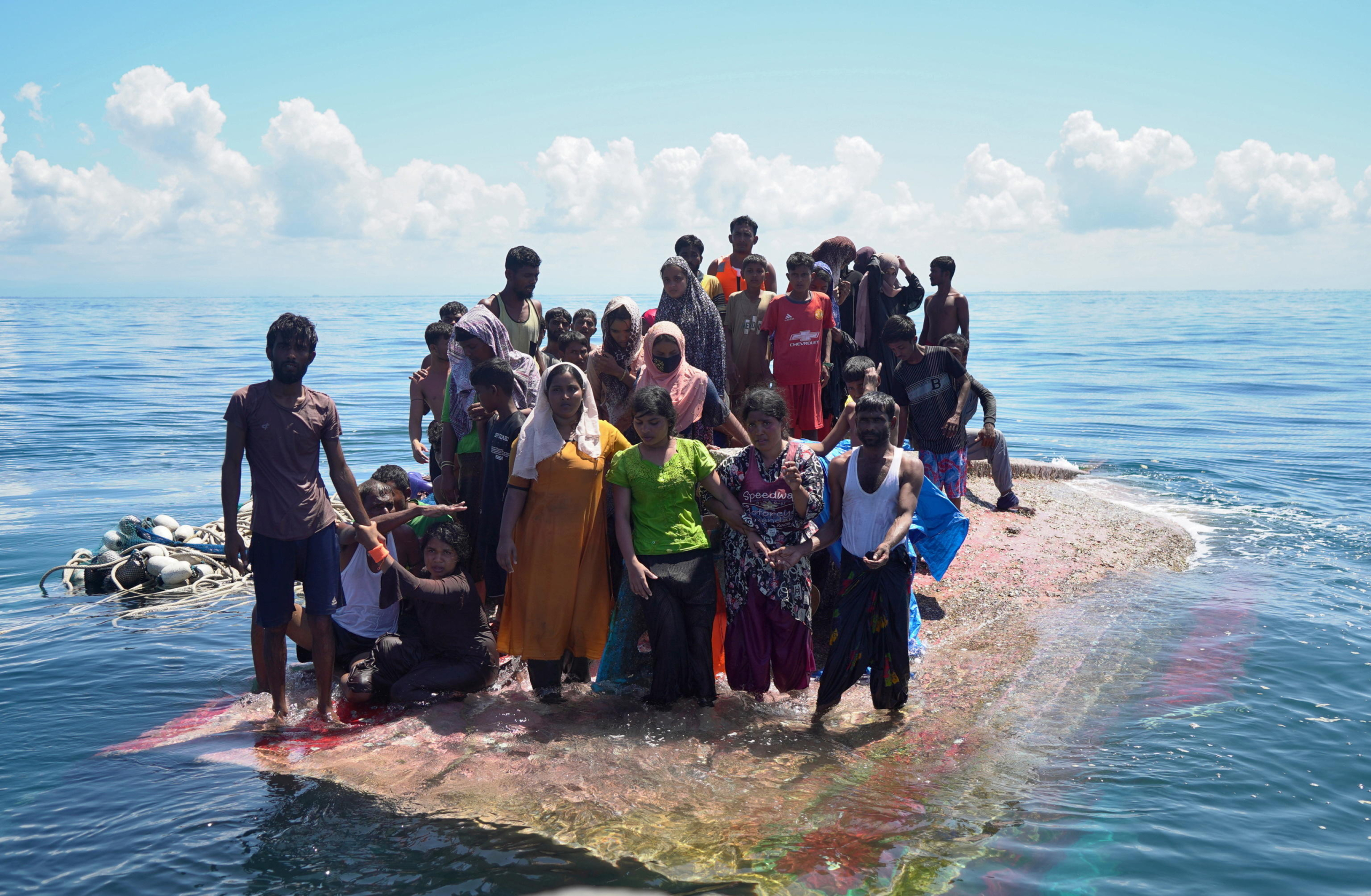 epa11756206 Members of the Rohingya ethnic minority stand on a capsized wooden boat as they wait to be rescued by a National Search and Rescue boat in the waters off West Aceh, Indonesia, 21 March 2024.  EPA/ZAINAL ABIDIN