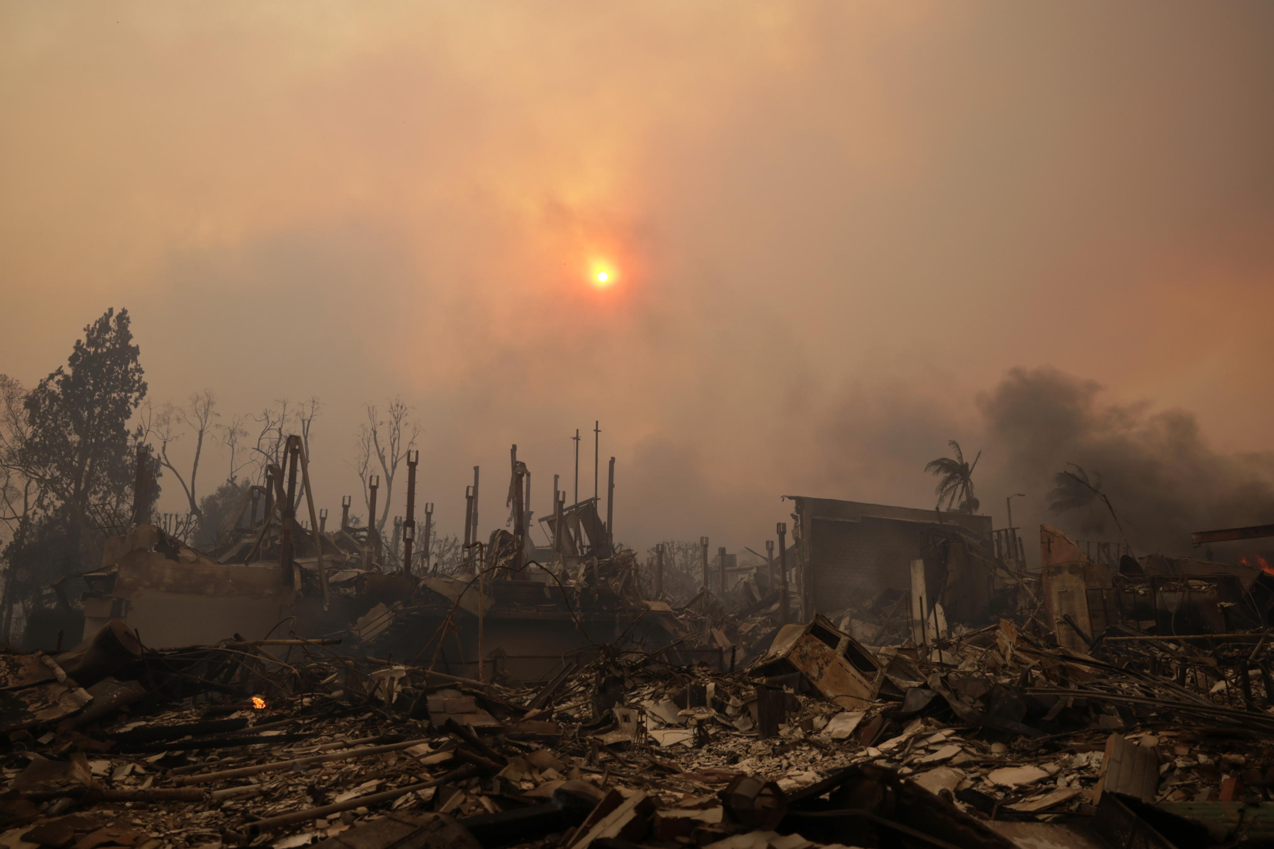 epaselect epa11813904 The sun shines through smoke above ruins of homes from the Palisades wildfire in the Pacific Palisades neighborhood of Los Angeles, California, USA, 08 January 2025. According to data from California Department of Forestry and Fire Protection (CAL FIRE), multiple wildfires are burning across thousands of acres and forced tens of thousands of evacuations in the Los Angeles area.  EPA/ALLISON DINNER