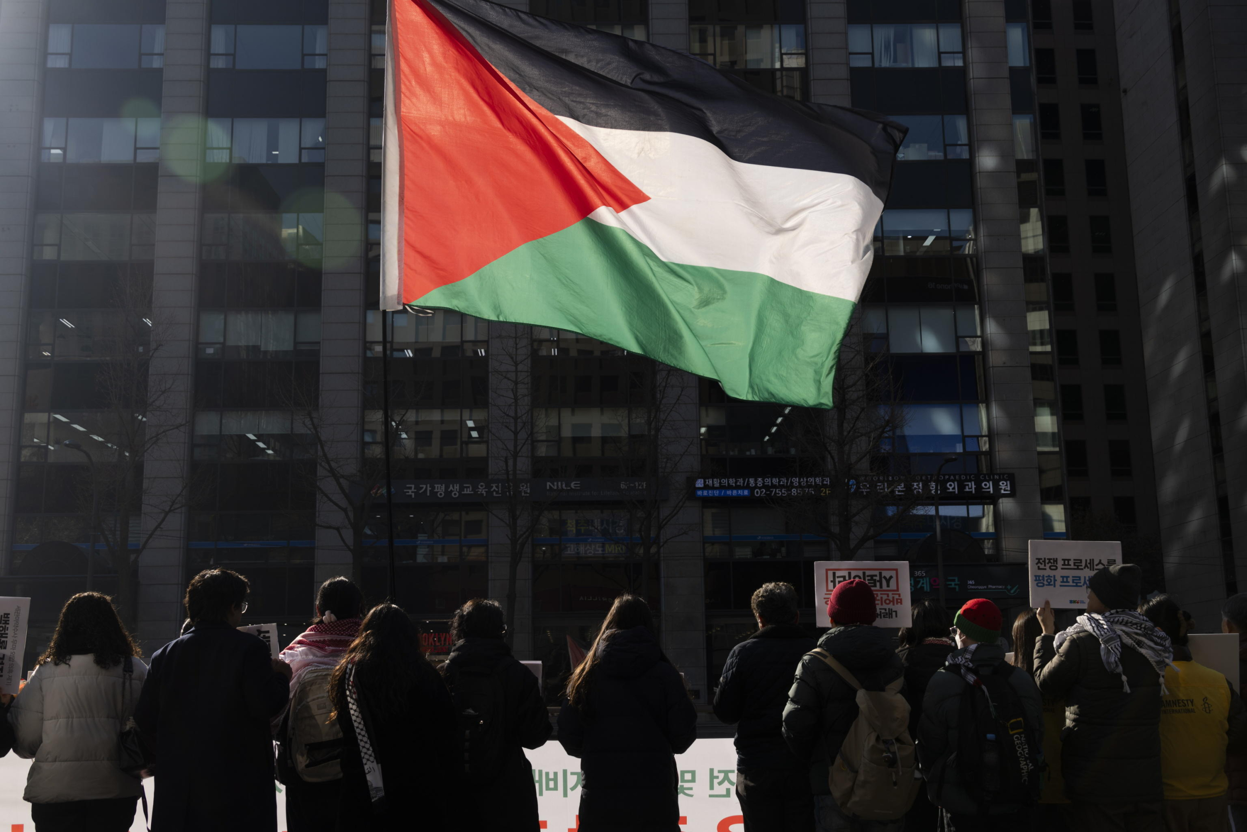 epa11829738 Members of Action4Palestine Korea hold up a Palestinian flag during a rally outside the Israeli embassy in Seoul, South Korea, 17 January 2025. Protesters gathered to demand that Israel approve a Gaza ceasefire and hostage deal after Israeli Prime Minister Benjamin Netanyahu delayed a cabinet vote on the agreement on 16 January.  EPA/JEON HEON-KYUN