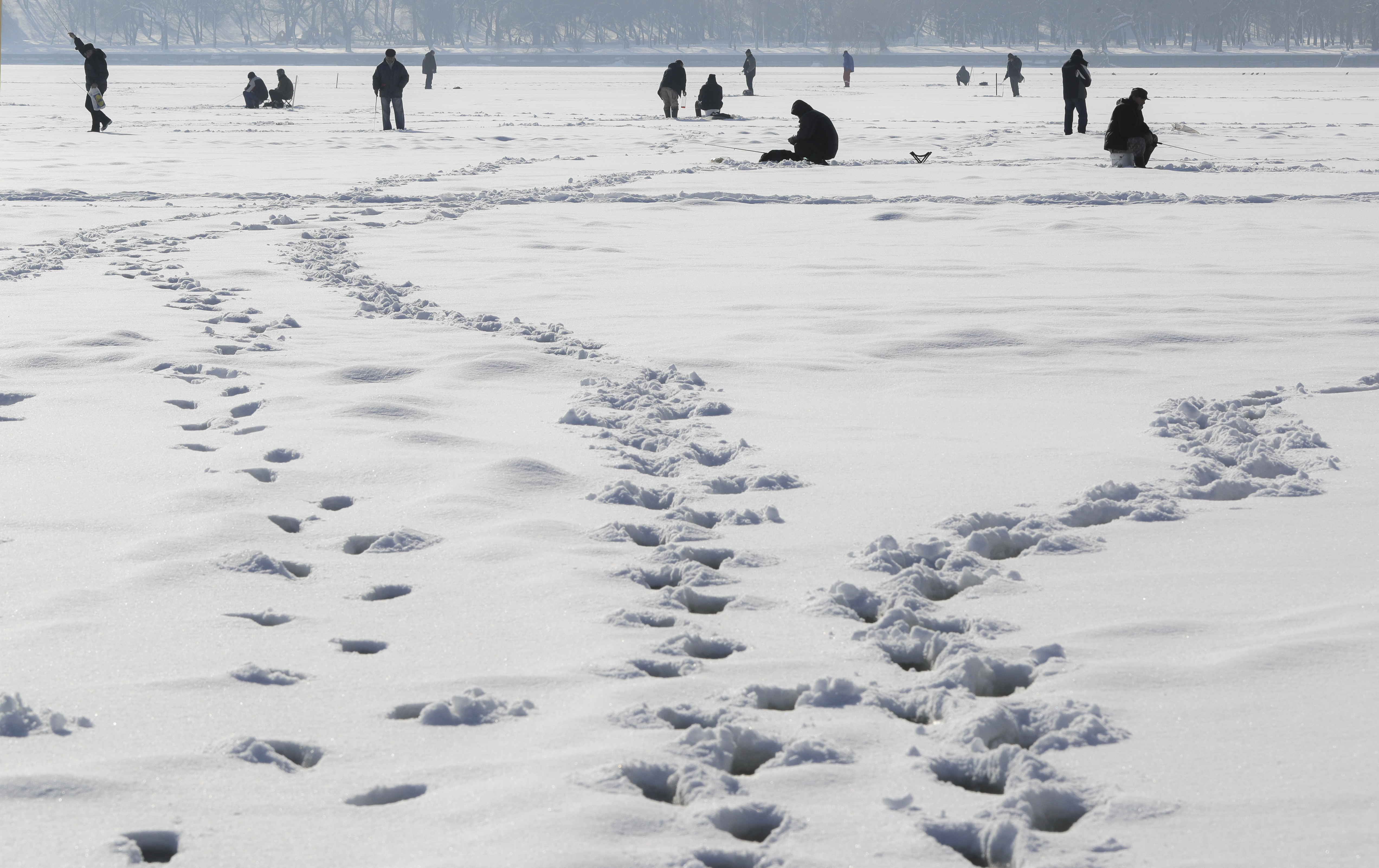 People fish on a frozen lake on the outskirts of Bucharest, Romania, Friday, Jan. 13, 2017. The Romanian capital experienced milder weather after a week of blizzards and extreme cold that caused a major disruption of the road and railway transport.(AP Photo/Vadim Ghirda)