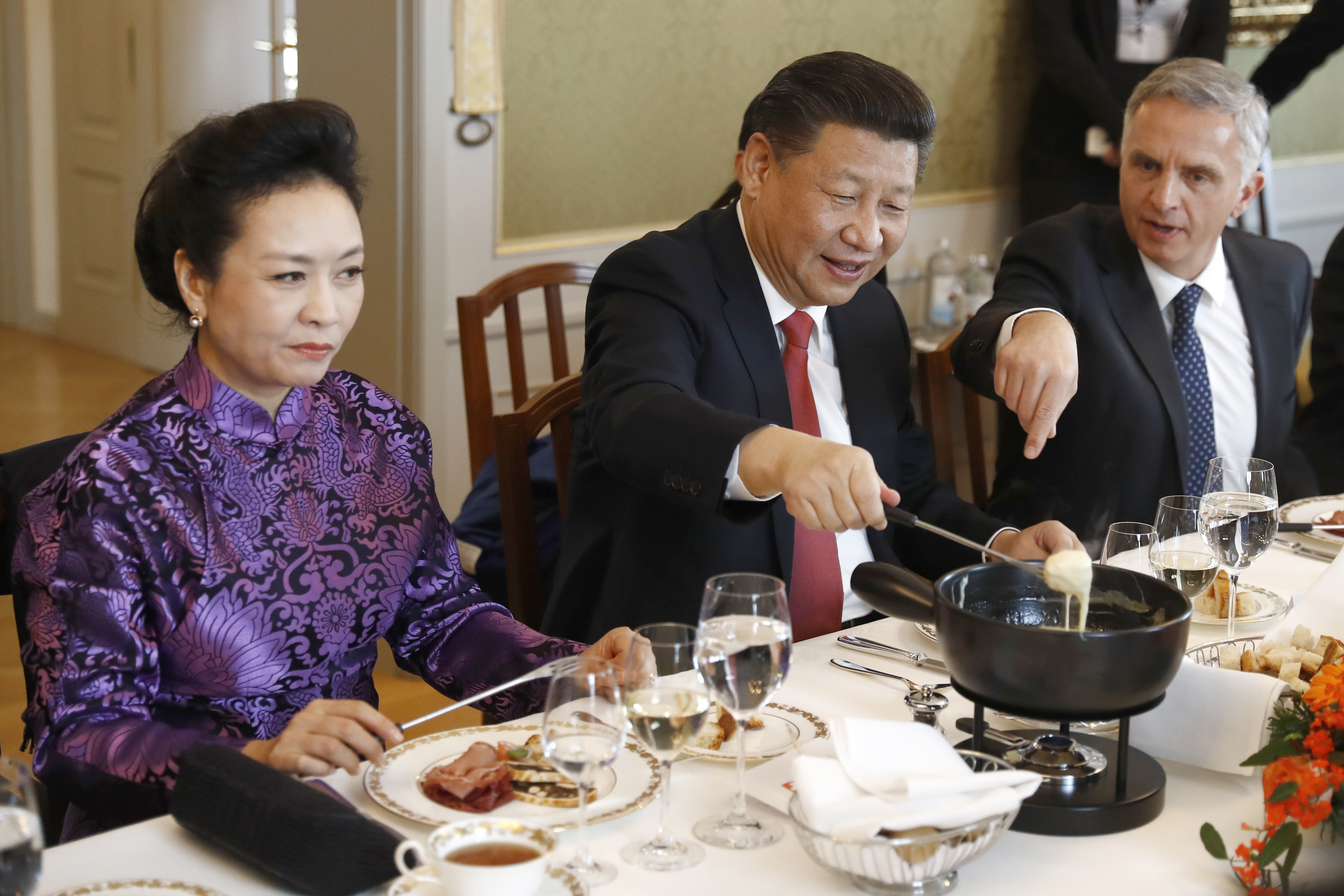 El presidente de China, Xi Jinping, en el centro, su esposa Peng Liyuan, a la izquierda, y el ministro suizo de Exteriores, Didier Burkhalter, comen queso suizo durante una comida en la visita de estado de dos días de Xi a Suiza, en Berna, Suiza, el lunes 16 de enero de 2017.  (Peter Klaunzer/Pool Foto via AP)