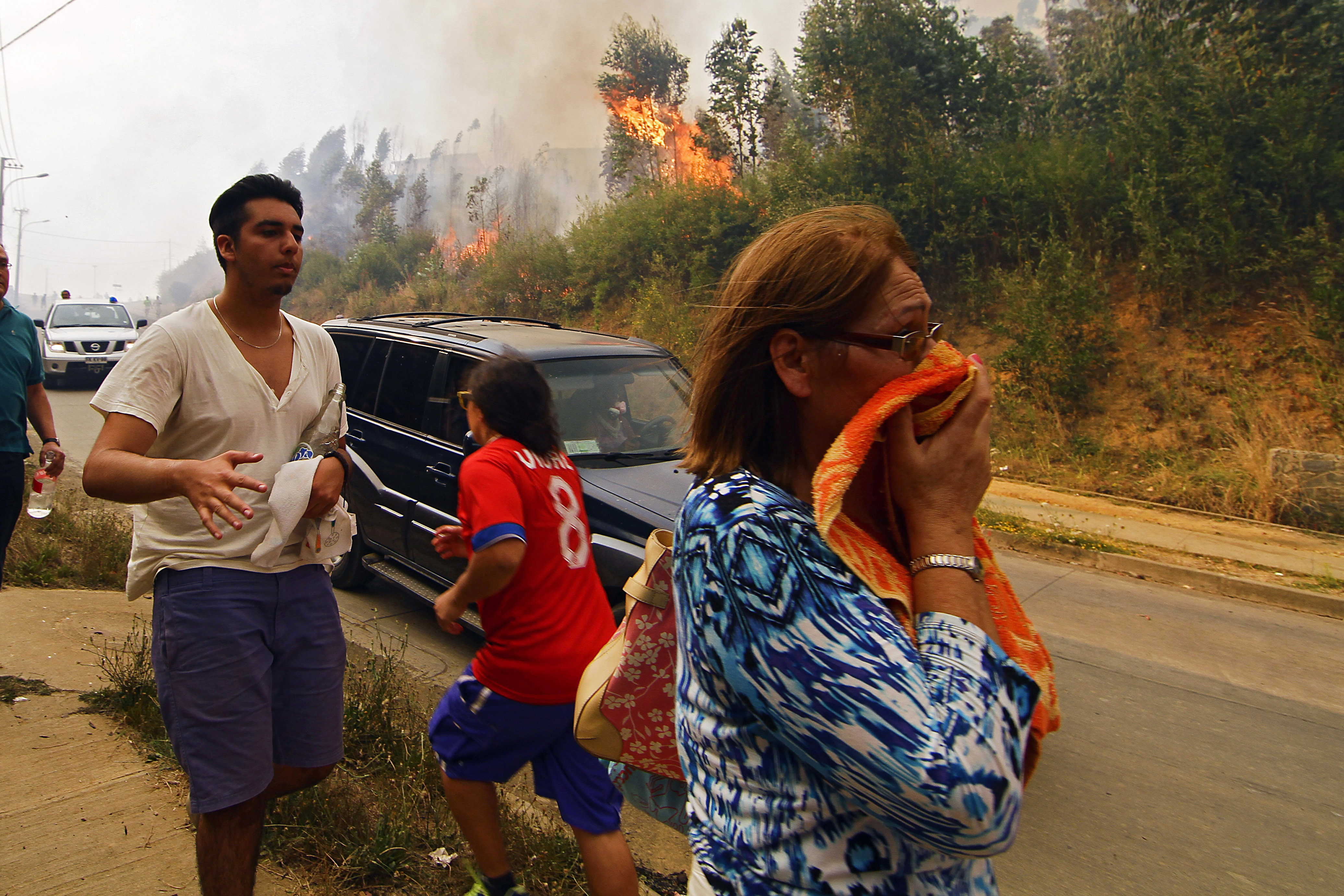 People react to the advancement of a forest fire in Hualañe, a community in Concepcion, Chile, Wednesday, Jan. 25, 2017. The worst forest fires in Chile's history were uncontrolled on Wednesday, killing a firefighter and two policemen caught in the flames as they tried to help families in rural communities, authorities said. (Alejandro Zoñez/Aton via AP) NO PUBLICAR EN CHILE