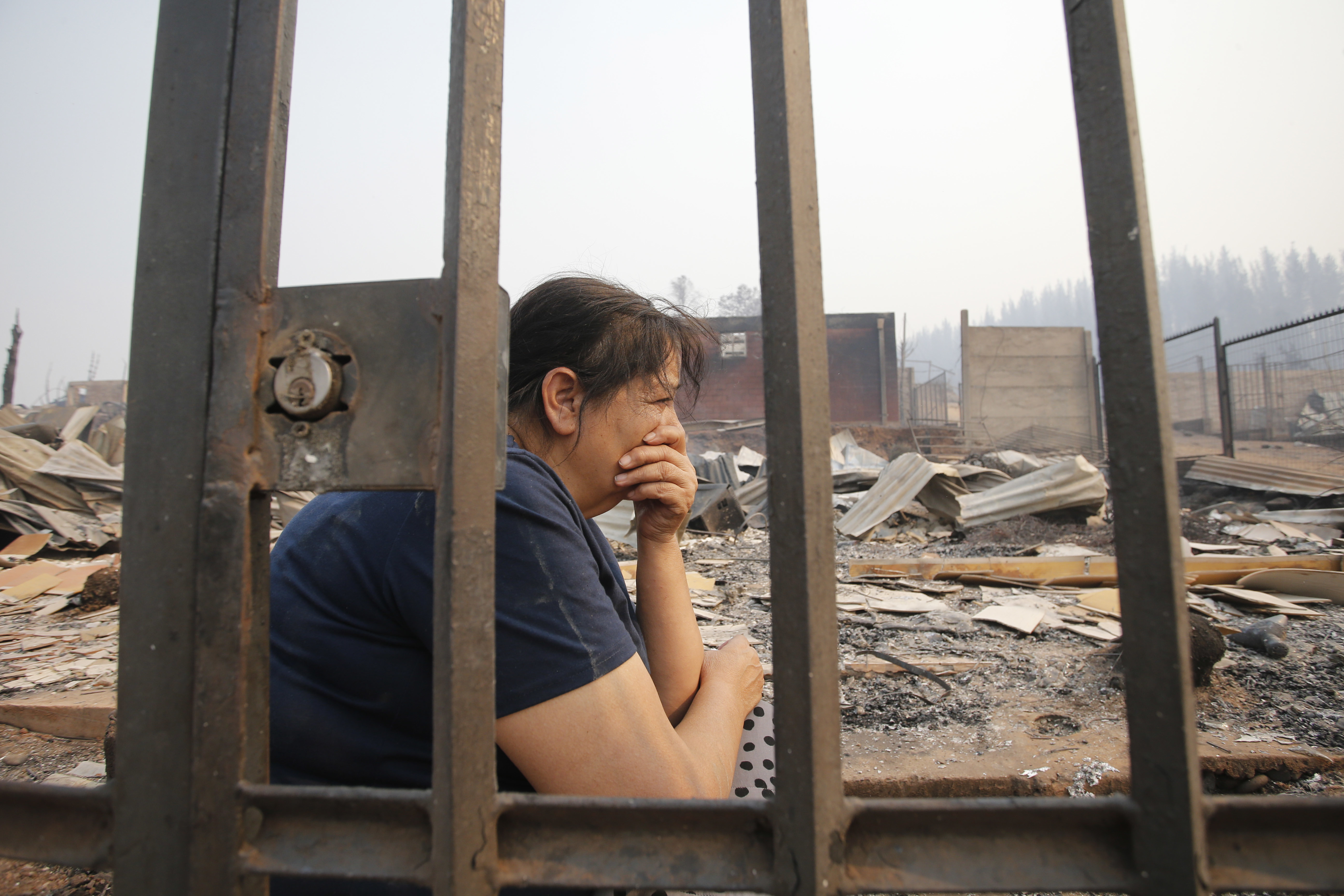 A woman sits on remains of a home destroyed by fire in Santa Olga, Chile, Thursday, Jan. 26, 2017. Chilean officials say that the town of Santa Olga was consumed in the flames of the country's worst wildfires, but its 6,000 residents escaped unharmed. The flames engulfed the post office, a kindergarten, and hundreds of homes Thursday in the town located 220 miles (360 kilometers) south of the Chilean capital. (Javier Torres/Aton via AP) NO PUBLICAR EN CHILE - CHILE OUT