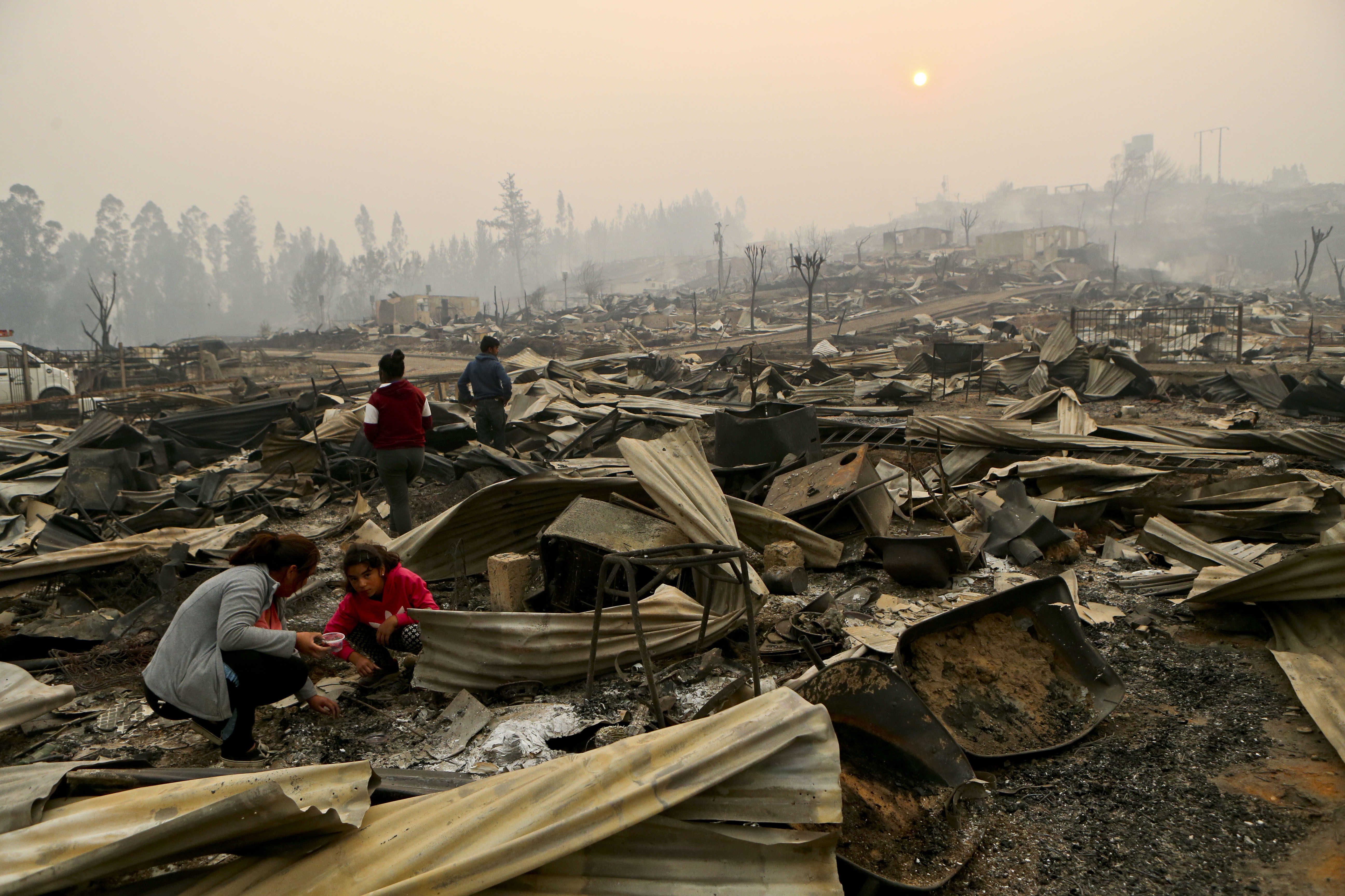 The Vega Salinas family searches what's left of their fire-destroyed home in Santa Olga, Chile, Thursday, Jan. 26, 2017. Officials say the town was consumed by the country's worst wildfires, engulfing the post office, a kindergarten and hundreds of homes. (AP Photo/Esteban Felix)