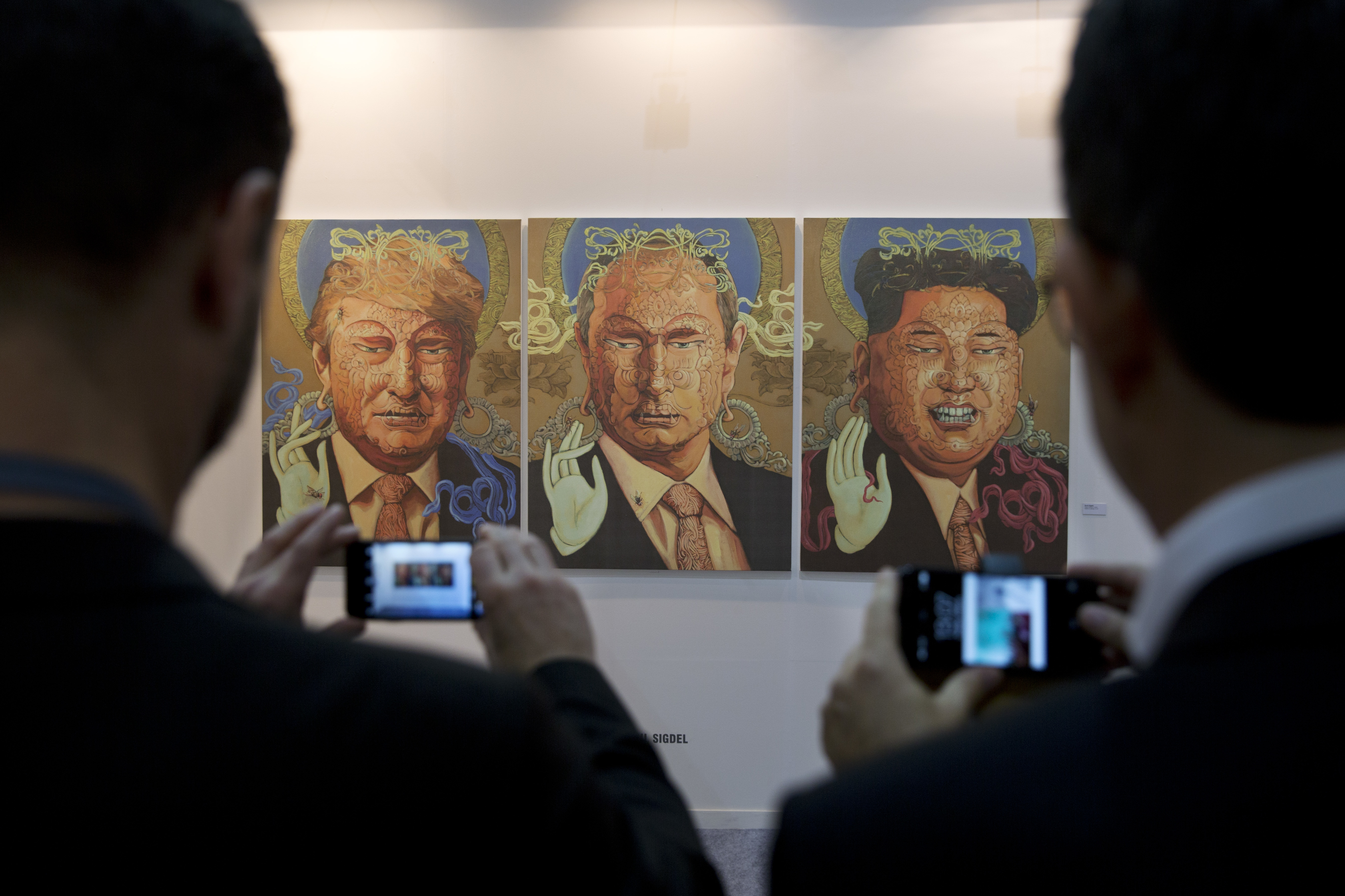 Art by Sunil Sigdel is displayed as spectators photograph during India Art Fair in New Delhi, India, Thursday, Feb. 2, 2017. The four day art fair brings together a number of modern and contemporary artists to present their works. (AP Photo/Tsering Topgyal)