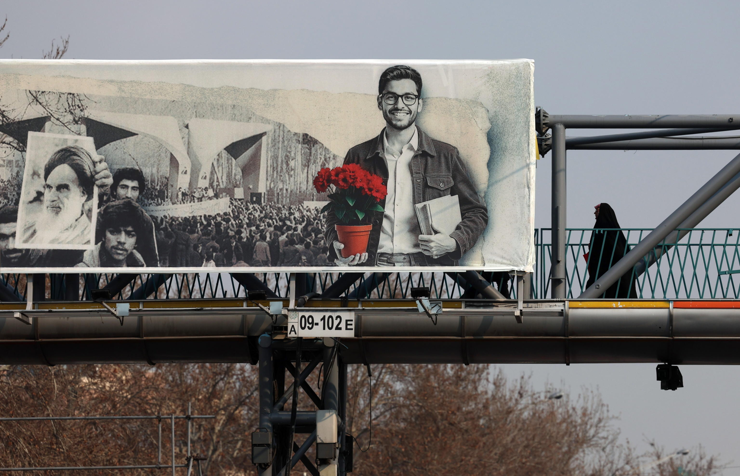 epa11865380 A veiled Iranian woman walks past a picture of Iranian late supreme leader Ayatollah Ruhollah Khomeini on a pedestrian bridge as the country marks the 46th anniversary of Khomeini's return from his Paris exile, in Tehran, Iran, 31 January 2025. Iran will celebrate its 45th revolution anniversary on 10 February 2025.  EPA/ABEDIN TAHERKENAREH