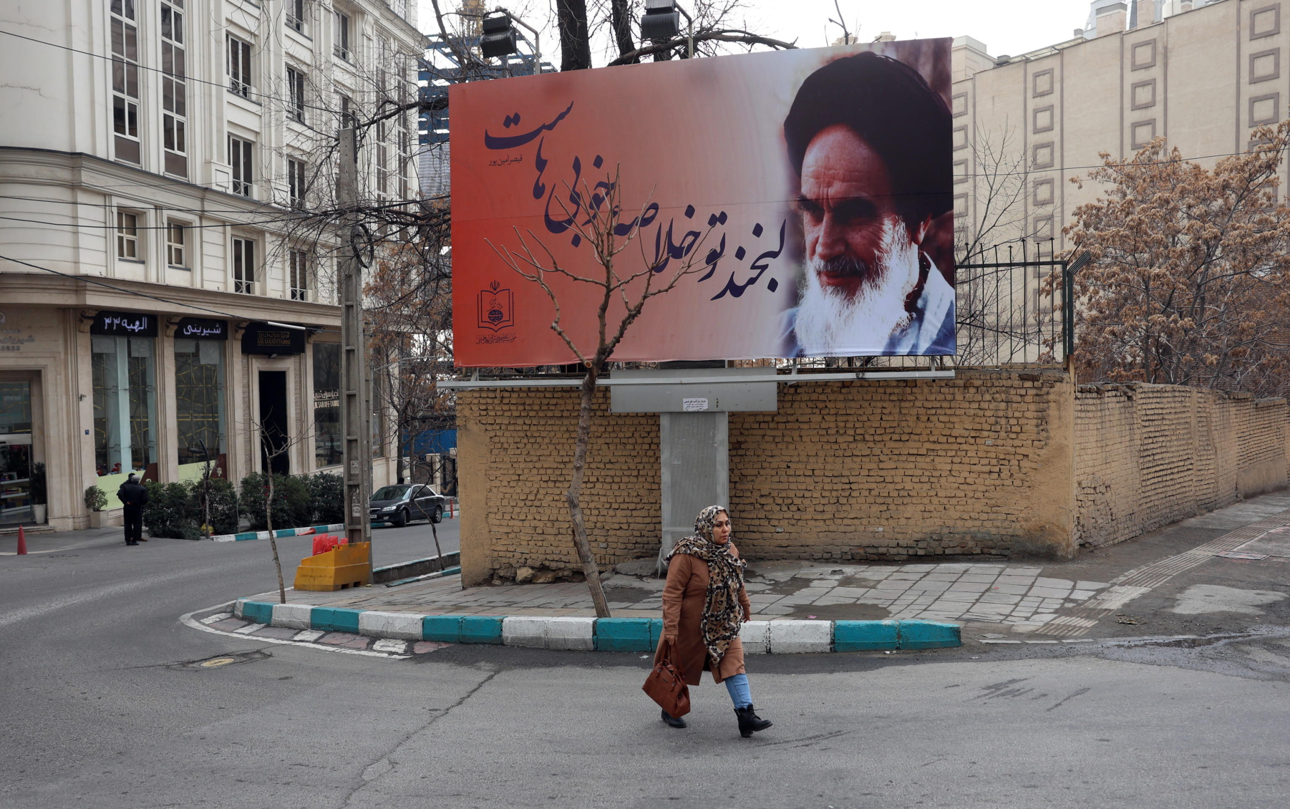 epa11865385 An Iranian woman walks past a picture of Iranian late supreme leader Ayatollah Ruhollah Khomeini as the country marks the 46th anniversary of Khomeini's return from his Paris exile, in Tehran, Iran, 31 January 2025. Iran will celebrate its 45th revolution anniversary on 10 February 2025.  EPA/ABEDIN TAHERKENAREH