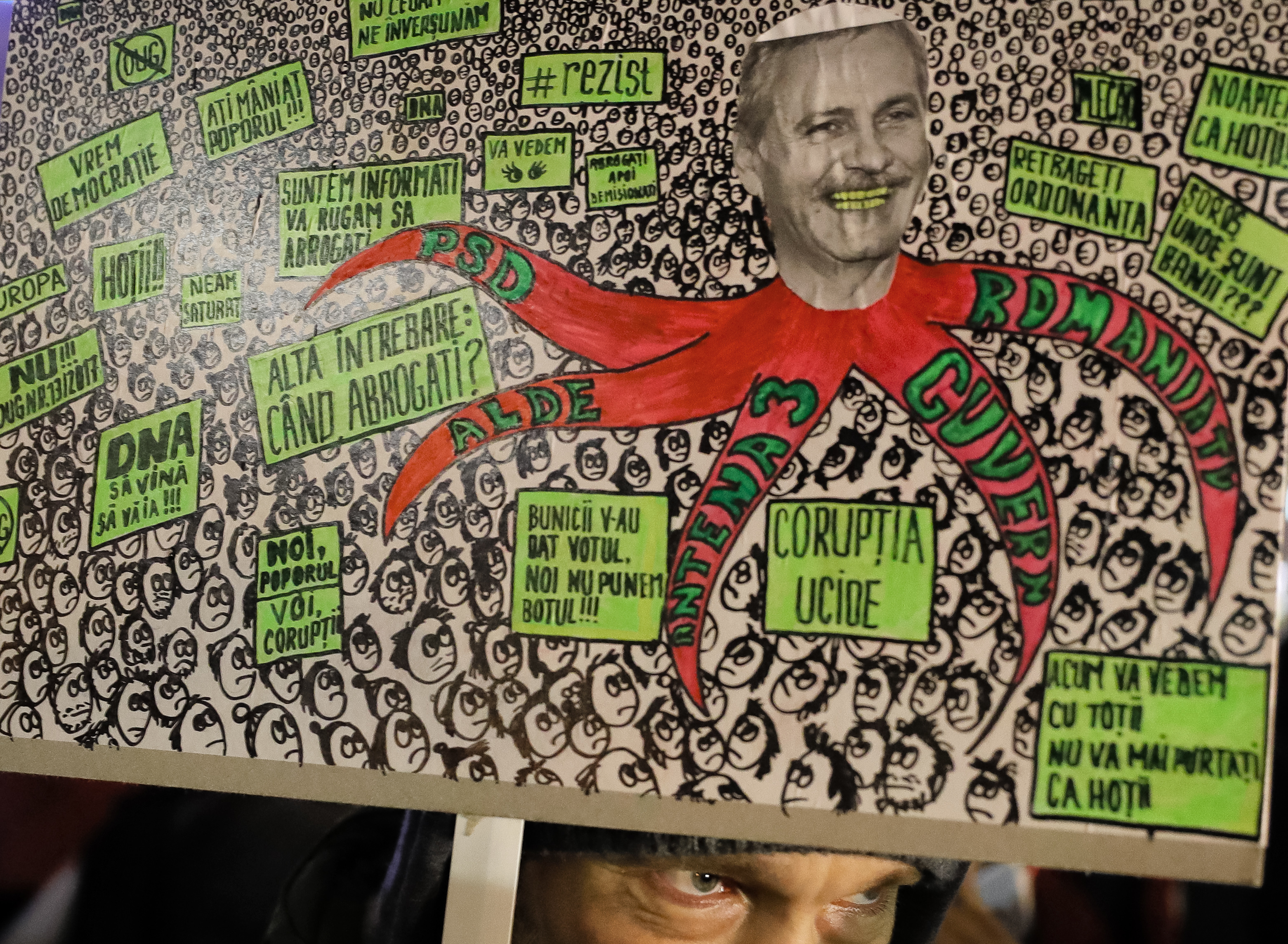 A anti-government protester holds a poster depicting the leader of the ruling Social Democratic party Liviu Dragnea in Bucharest, Romania, Tuesday, Feb. 7, 2017. Romania's president told lawmakers Tuesday the country is in a 