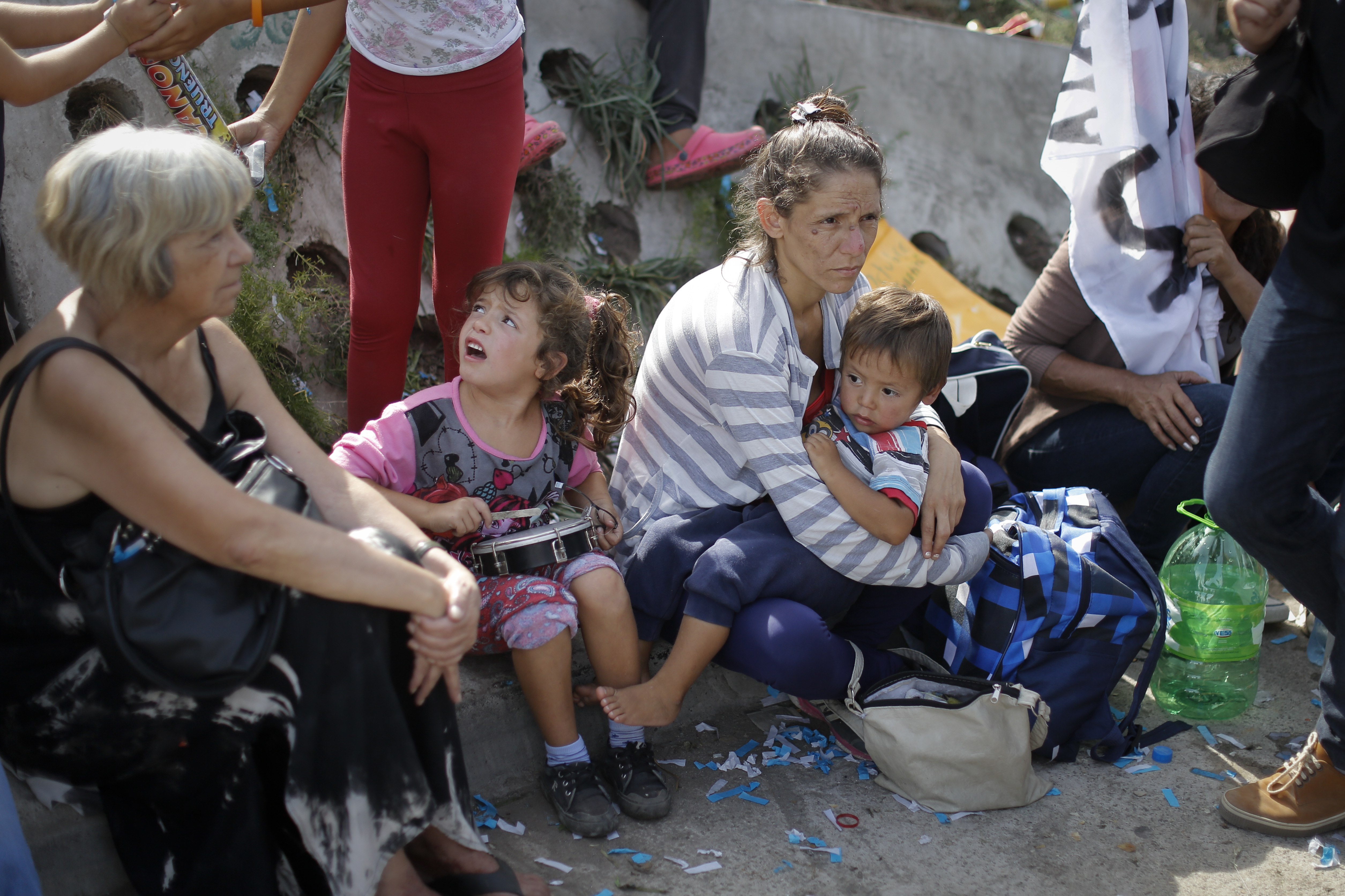 Under a blazing sun, women with children sit on the curb to rest during a demonstration in Buenos Aires, Tuesday, March 7, 2017. Argentina's most powerful unions brought tens of thousands of people into the capital's streets to protest government job cuts, the lifting of restrictions on imports and other policies of President Mauricio Macri. (AP Photo/Victor R. Caivano)