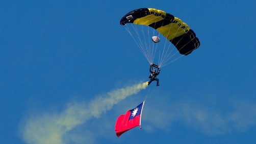 epa11786580 A Taiwanese paratrooper hoists the national flag during a live training session in Pingtung city, Taiwan, 20 December 2024. According to an 18 December report published by the United States Department of Defense (DoD), China continued to increase diplomatic, political, and military pressure against Taiwan in 2023.  EPA/RITCHIE B. TONGO